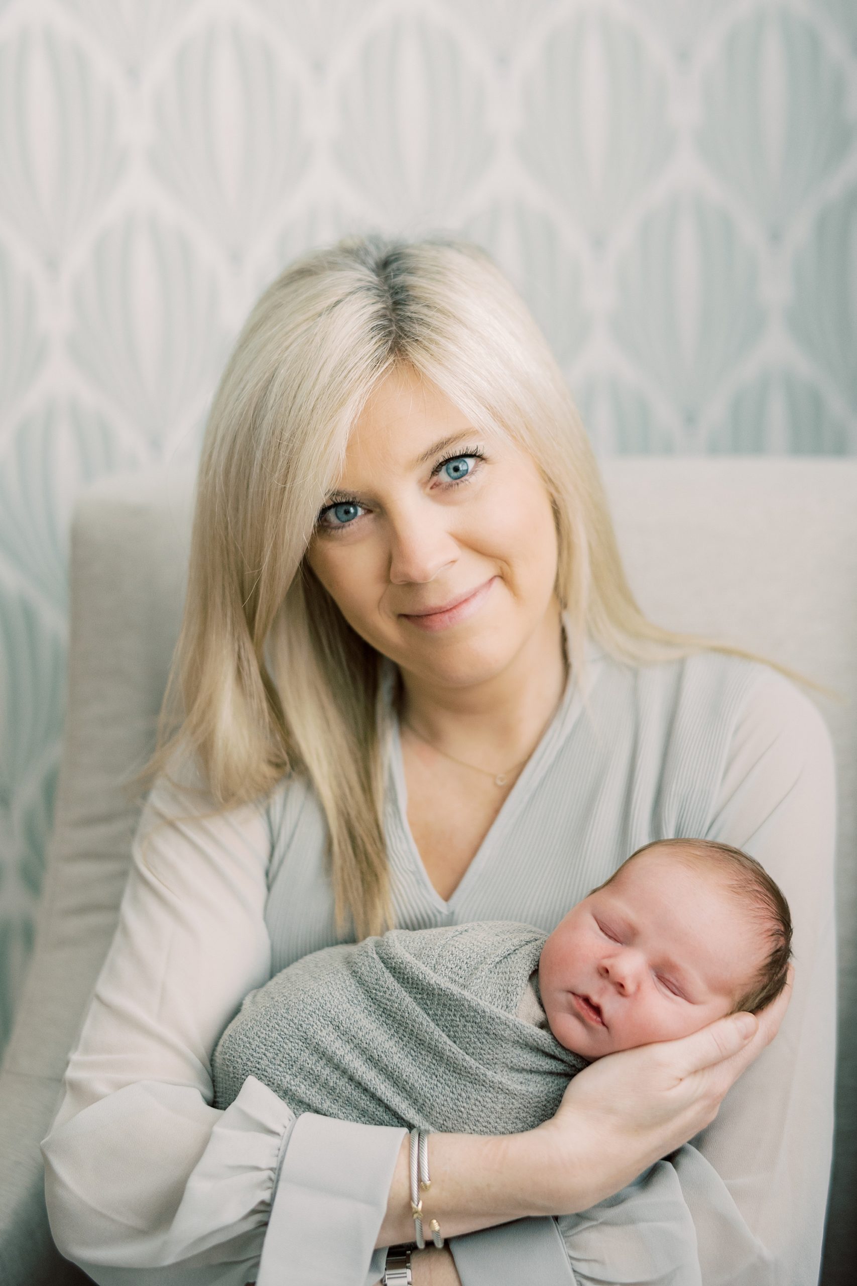 blonde woman holds son in sage green wrap 