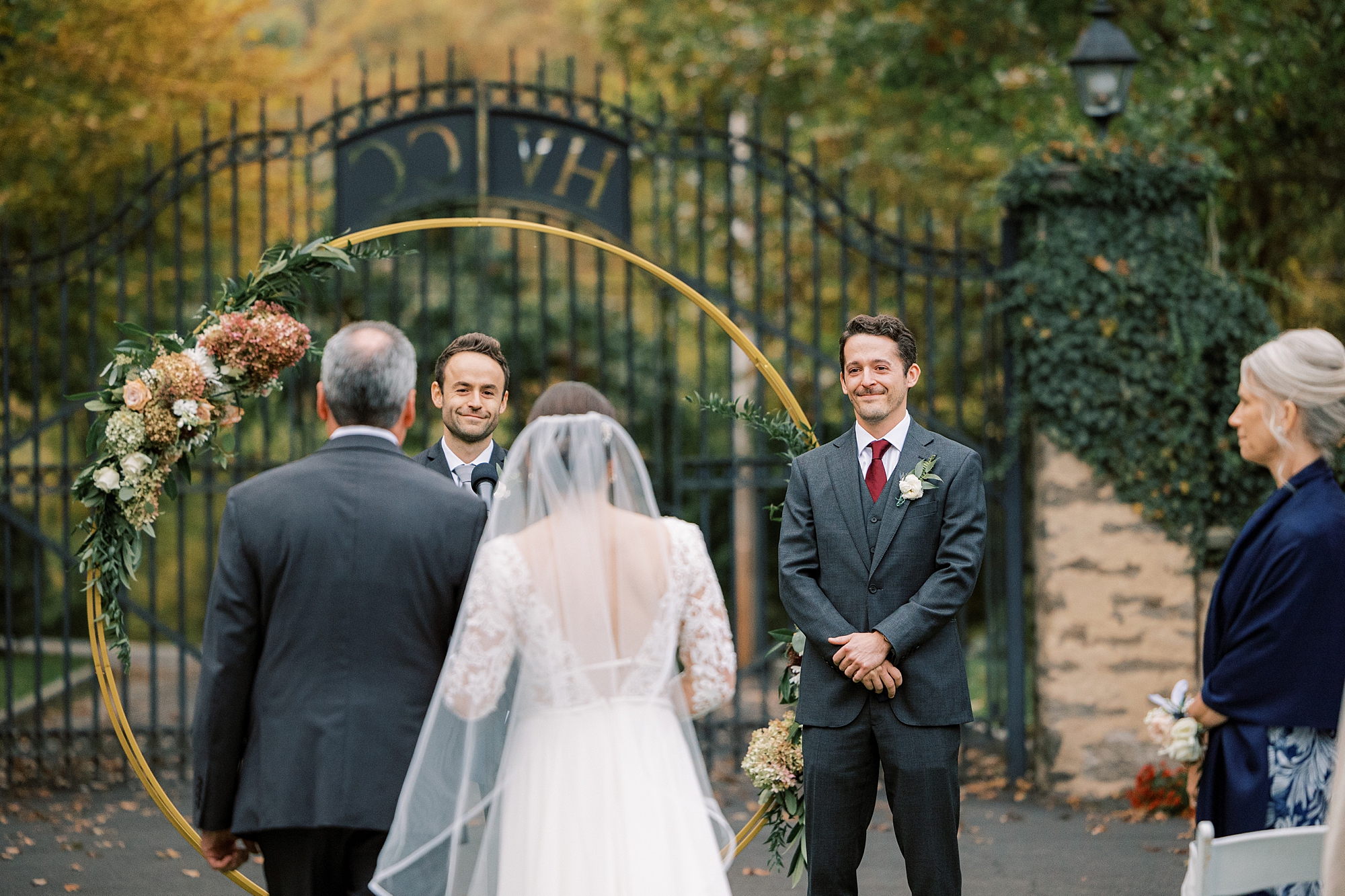 groom smiles at bride at the end of the aisle at Huntingdon Valley Country Club