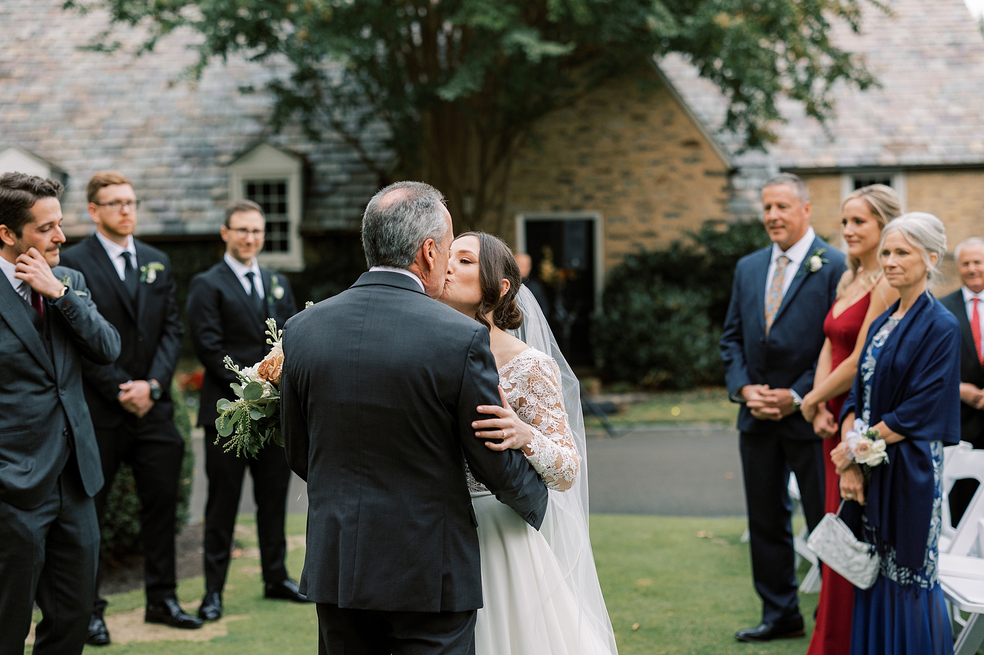 bride kisses father on cheek during wedding ceremony