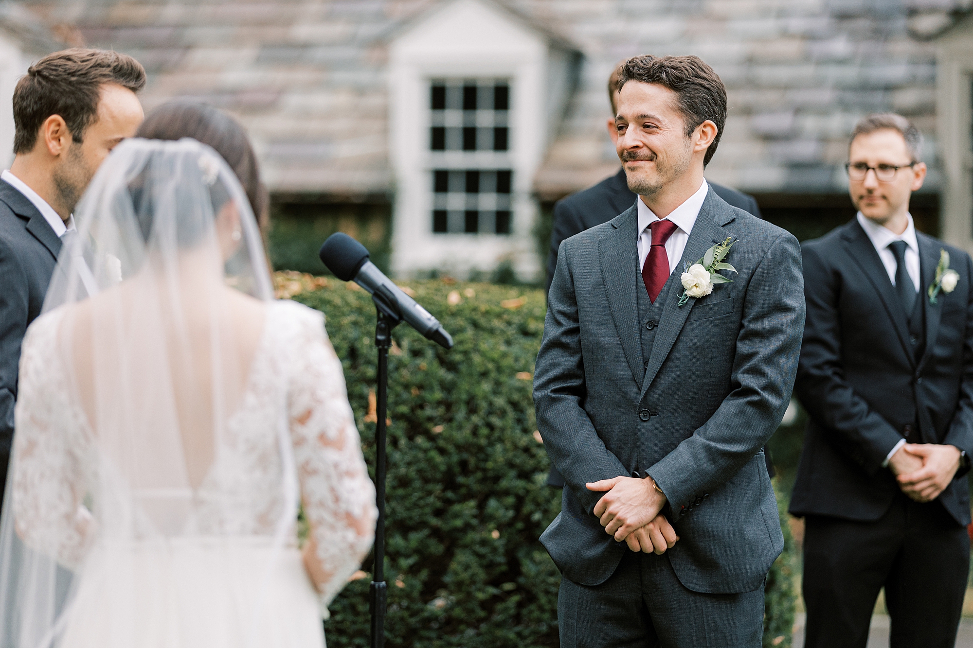 groom smiles at bride during wedding ceremony on lawn