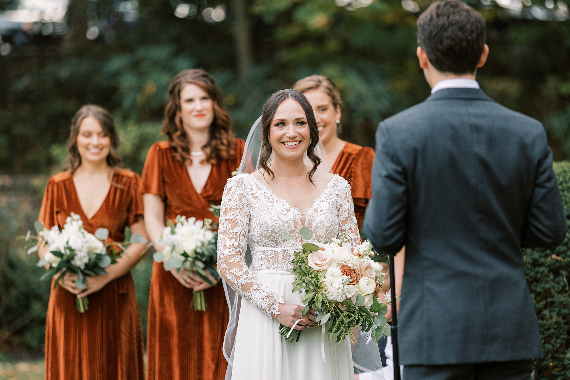 bride smiles at groom with bridesmaids in velvet gowns behind her
