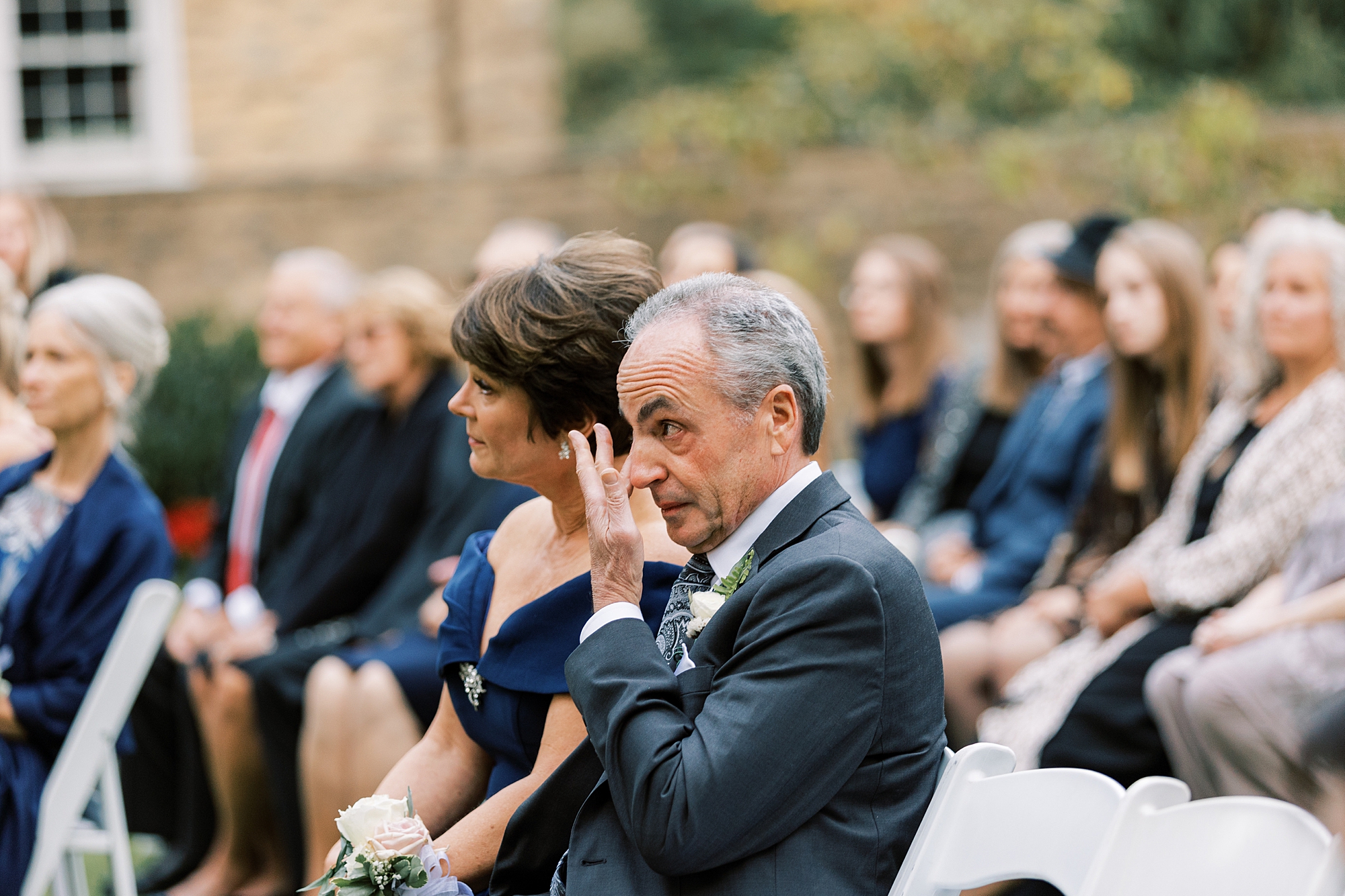 father wipes away tears during wedding ceremony on lawn at Huntingdon Valley Country Club