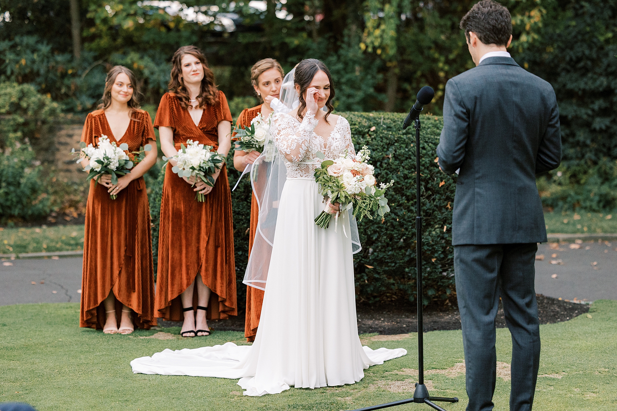 bride wipes away tear holding bouquet during fall wedding ceremony