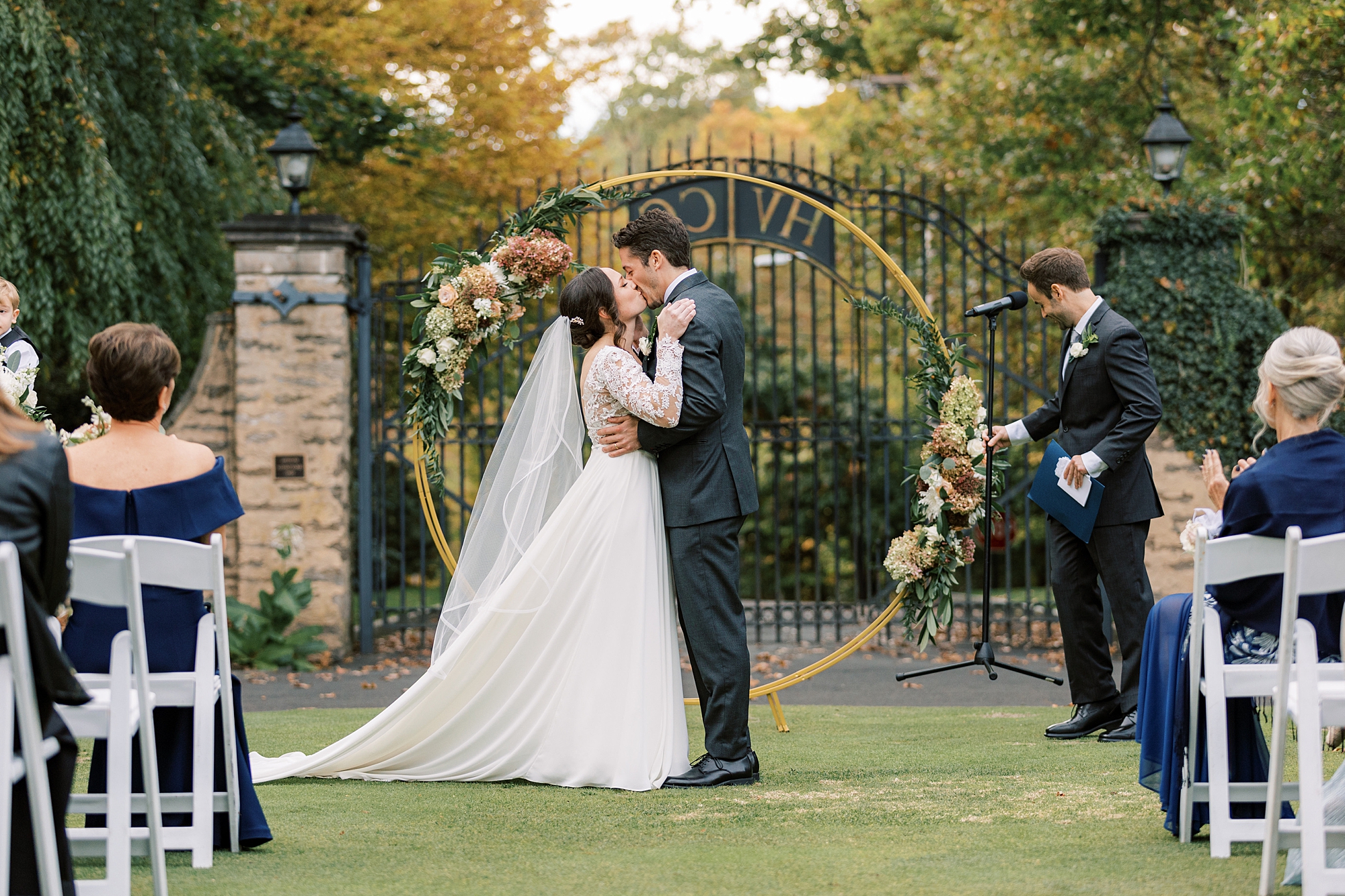 bride and groom kiss in front of gold circle arbor at Huntingdon Valley Country Club