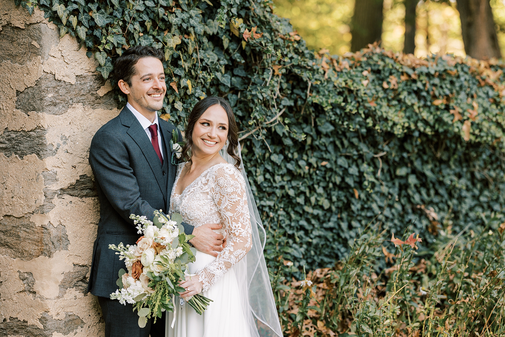 bride and groom hug by ivy wall at Huntingdon Valley Country Club