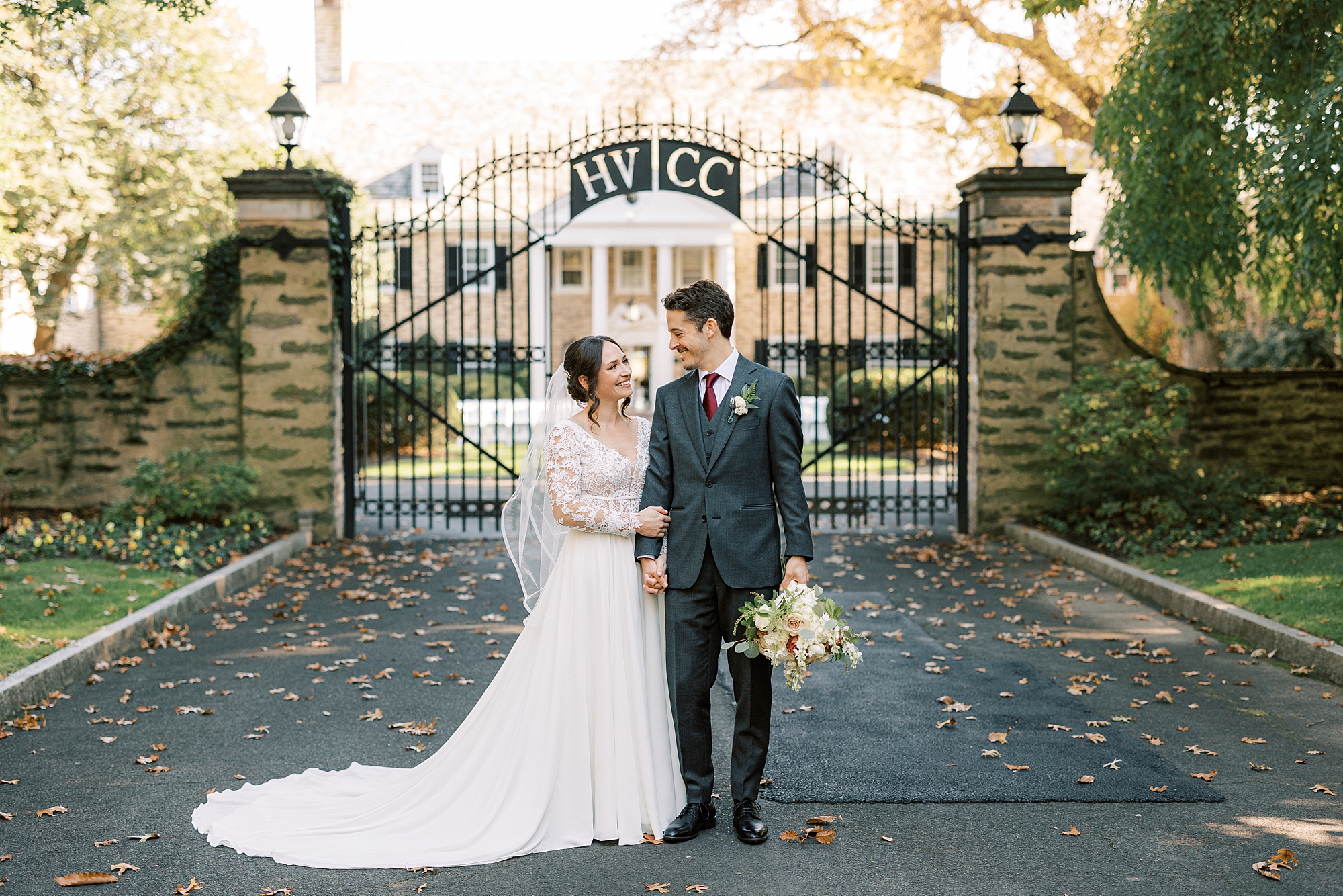 newlyweds stand in front of wrought iron gate at Huntingdon Valley Country Club