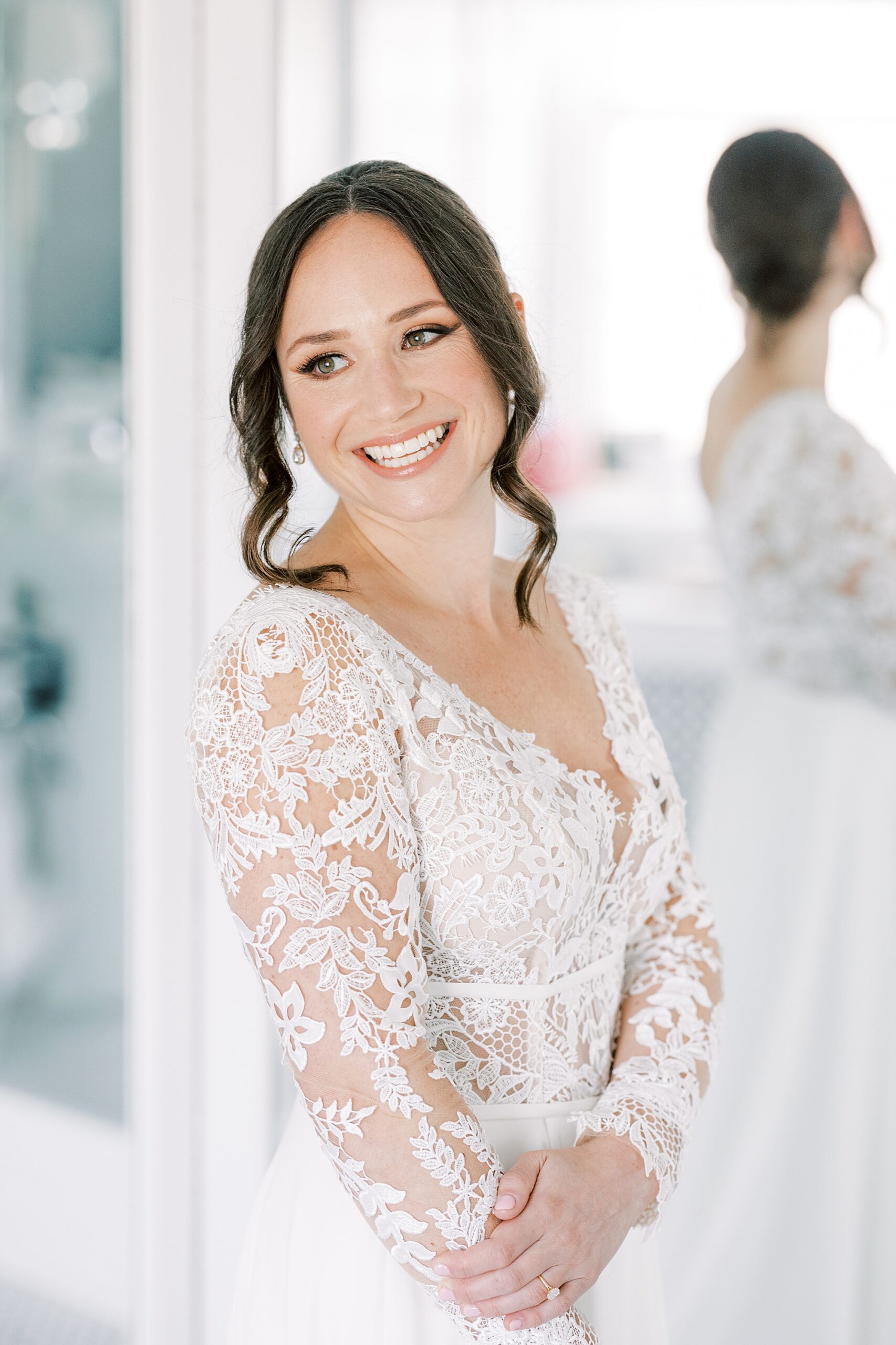 bride smiles looking over shoulder in lace-sleeved wedding gown