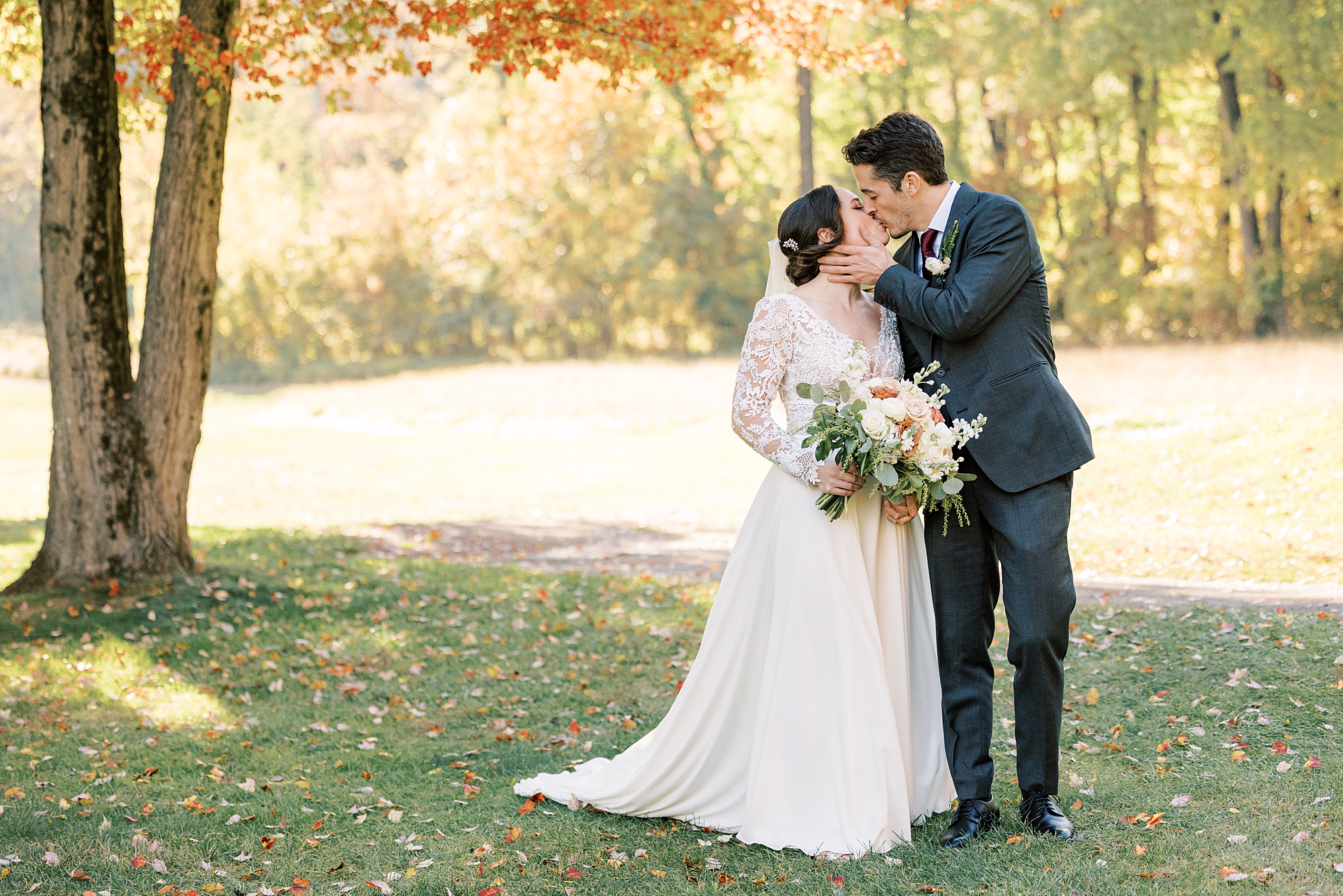 bride and groom kiss under yellow leaves of trees at Huntingdon Valley Country Club