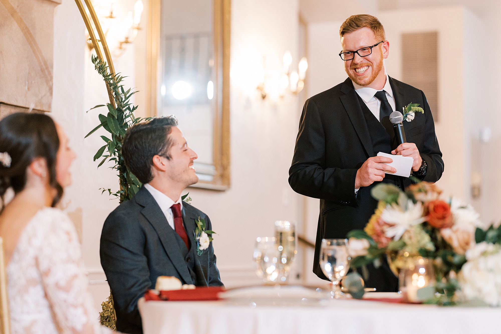 groom smiles at best man during toasts