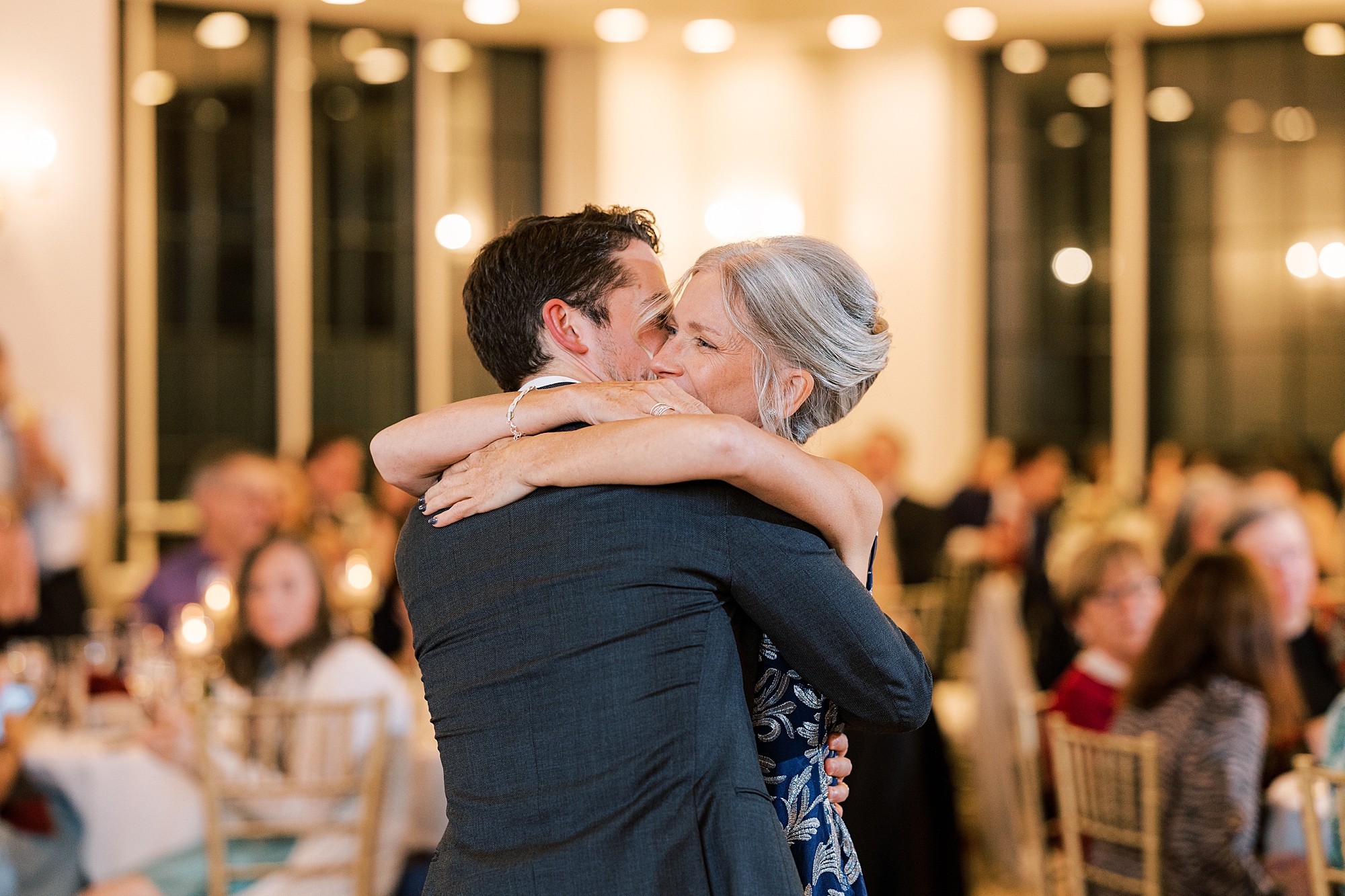 mother of the groom hugs him close during dance