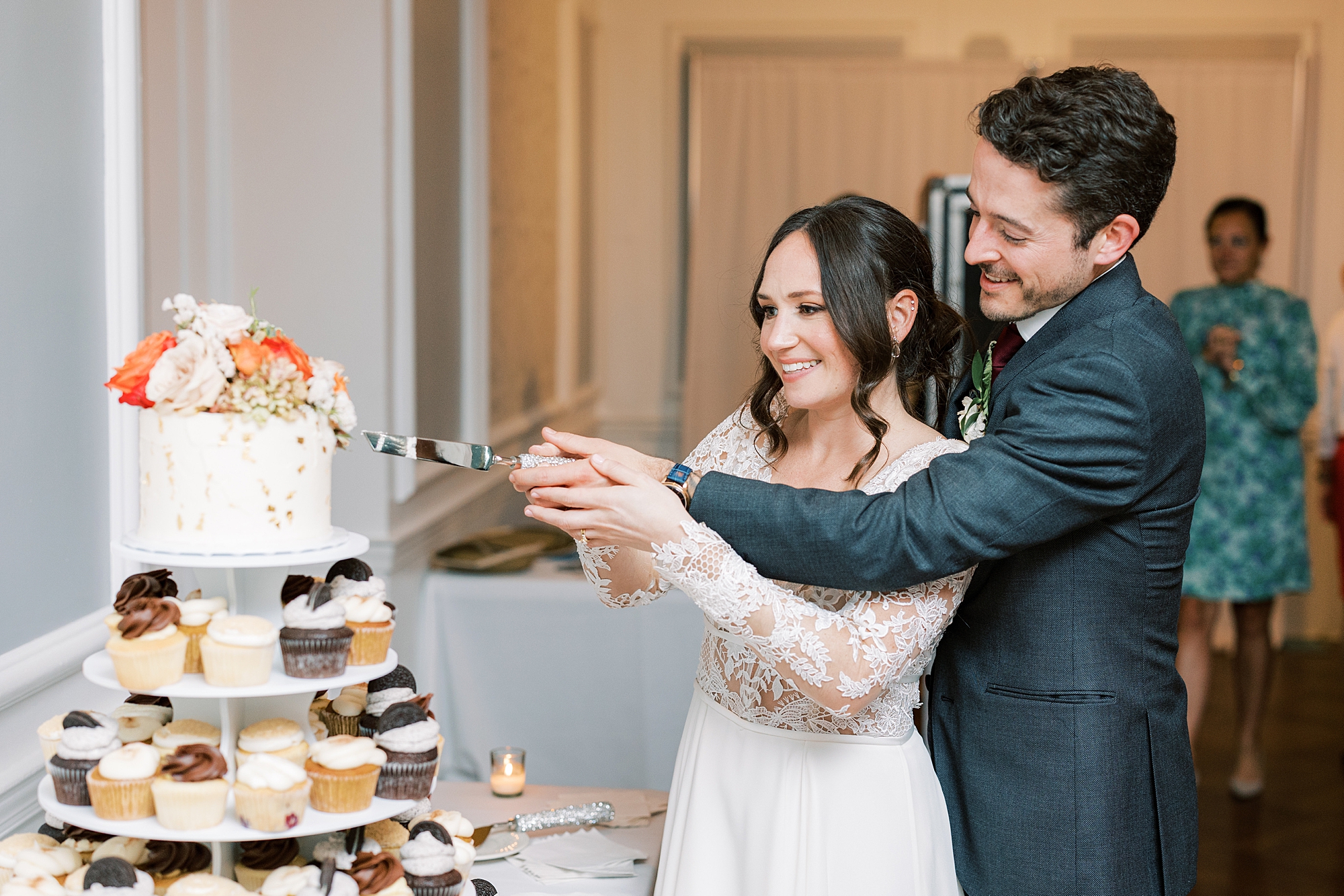 bride and groom cut wedding cake on top of cupcakes