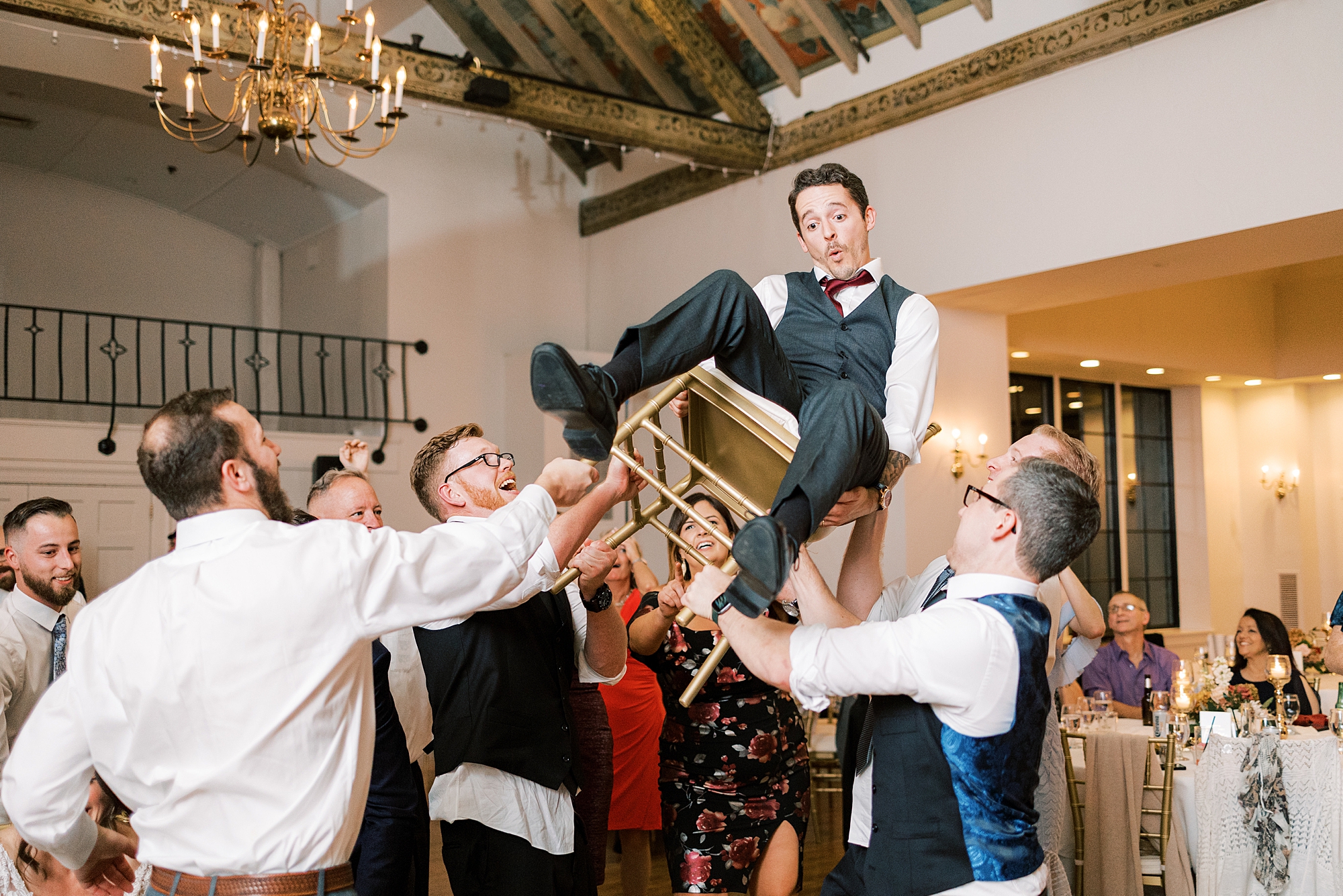 groomsmen lift groom up in chair during PA wedding reception