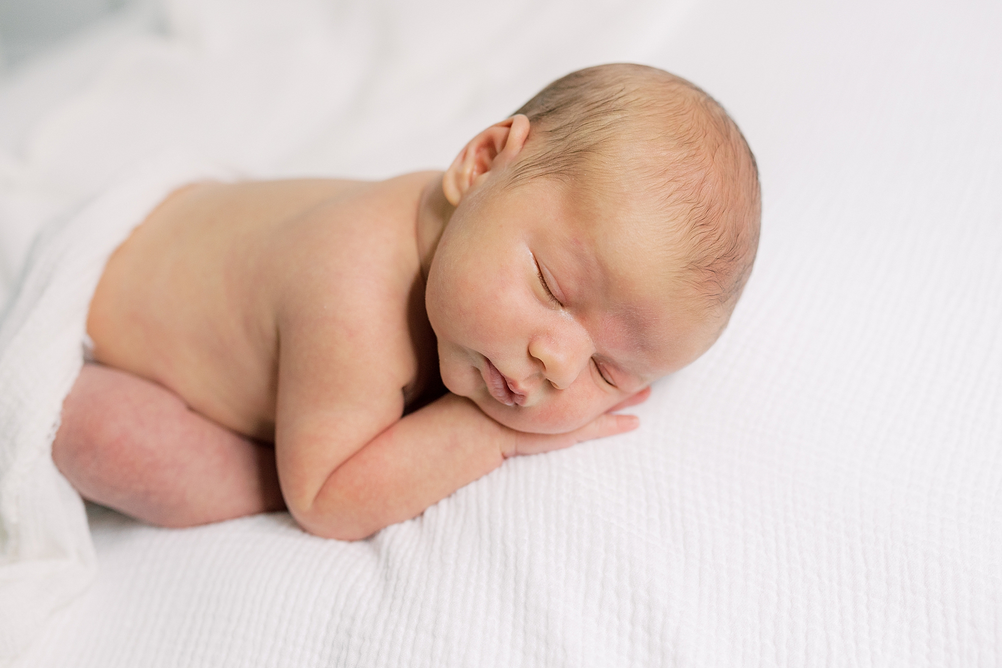 baby boy sleeps on white blanket during newborn portraits at home 