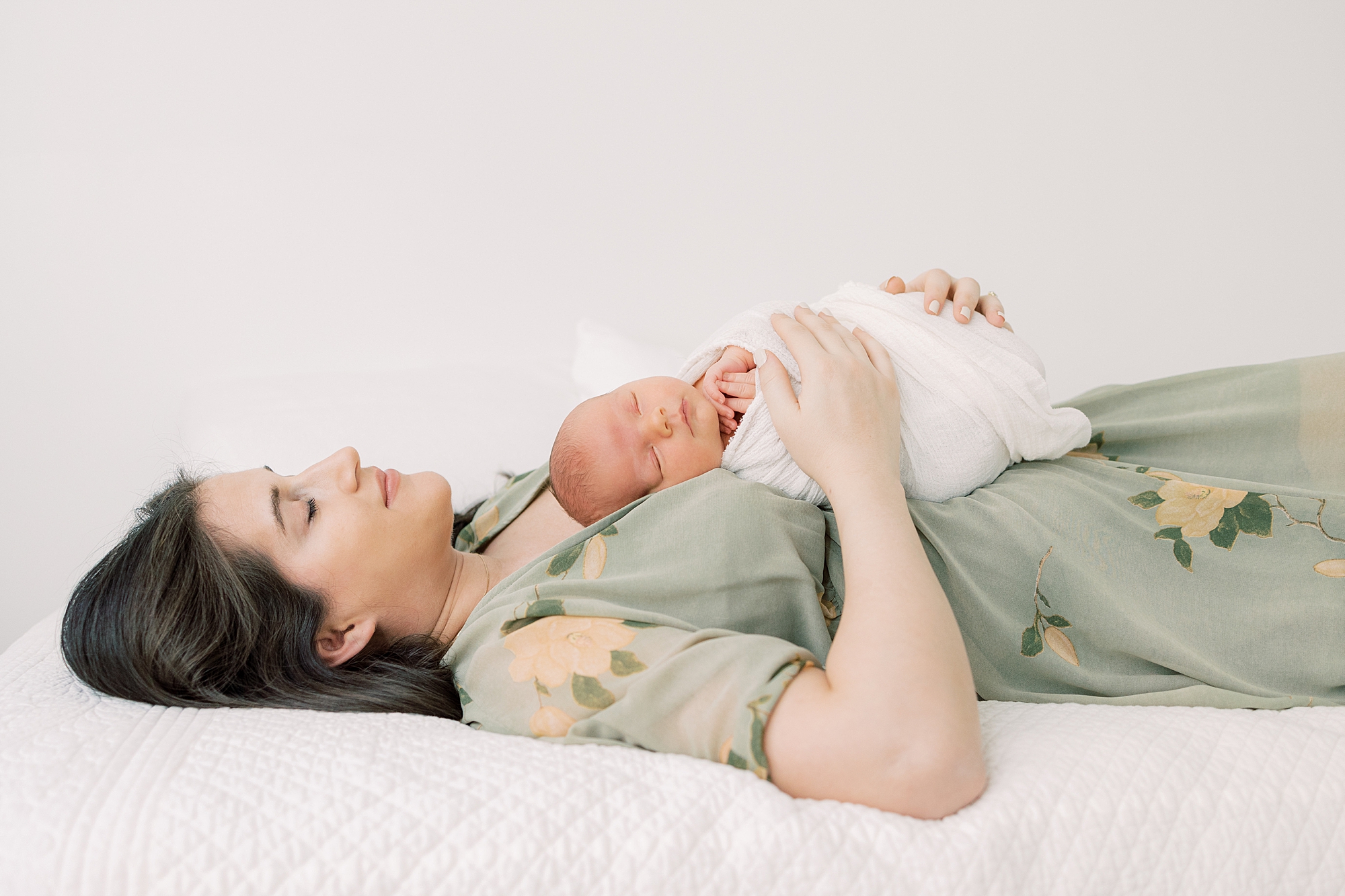 mother lays with baby boy on her chest during PA newborn portraits at home