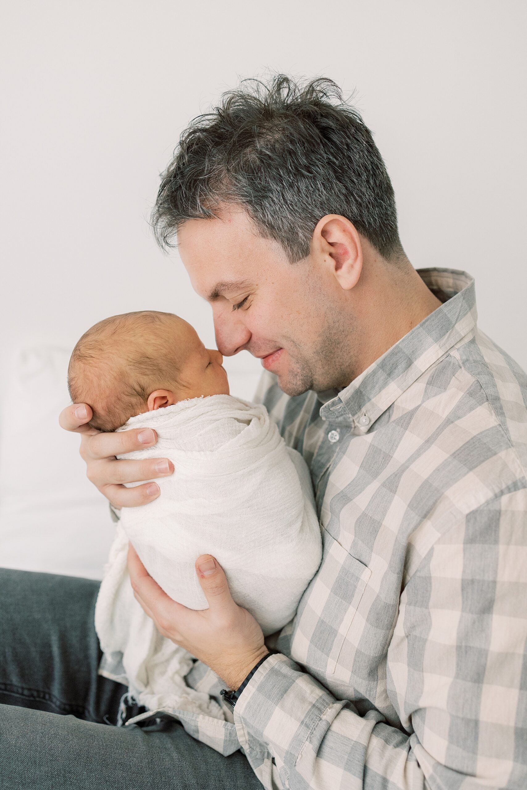 dad nuzzles baby's nose in white wrap during PA newborn portraits at home