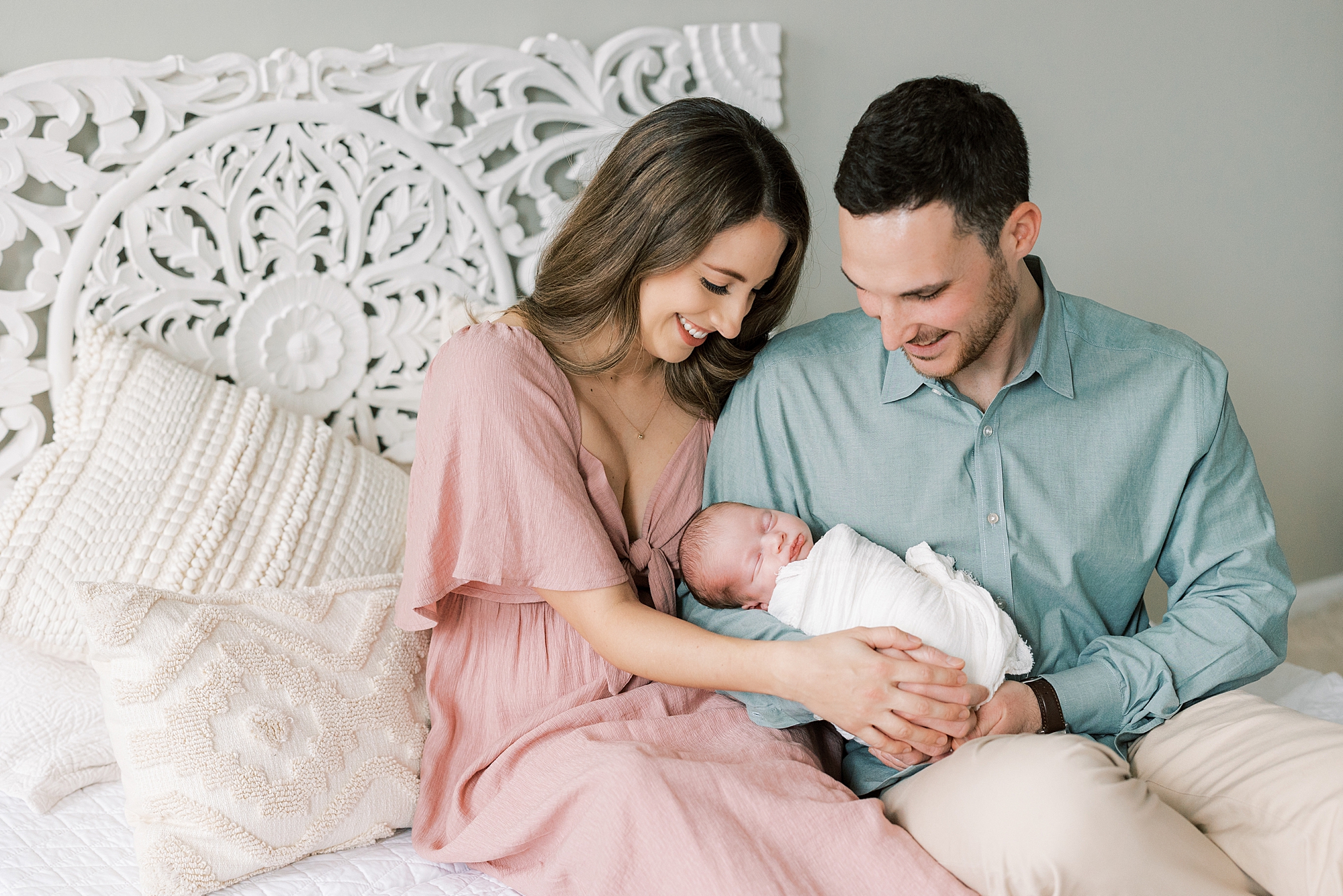 parents sit with newborn girl on bed during studio newborn session in Philadelphia PA