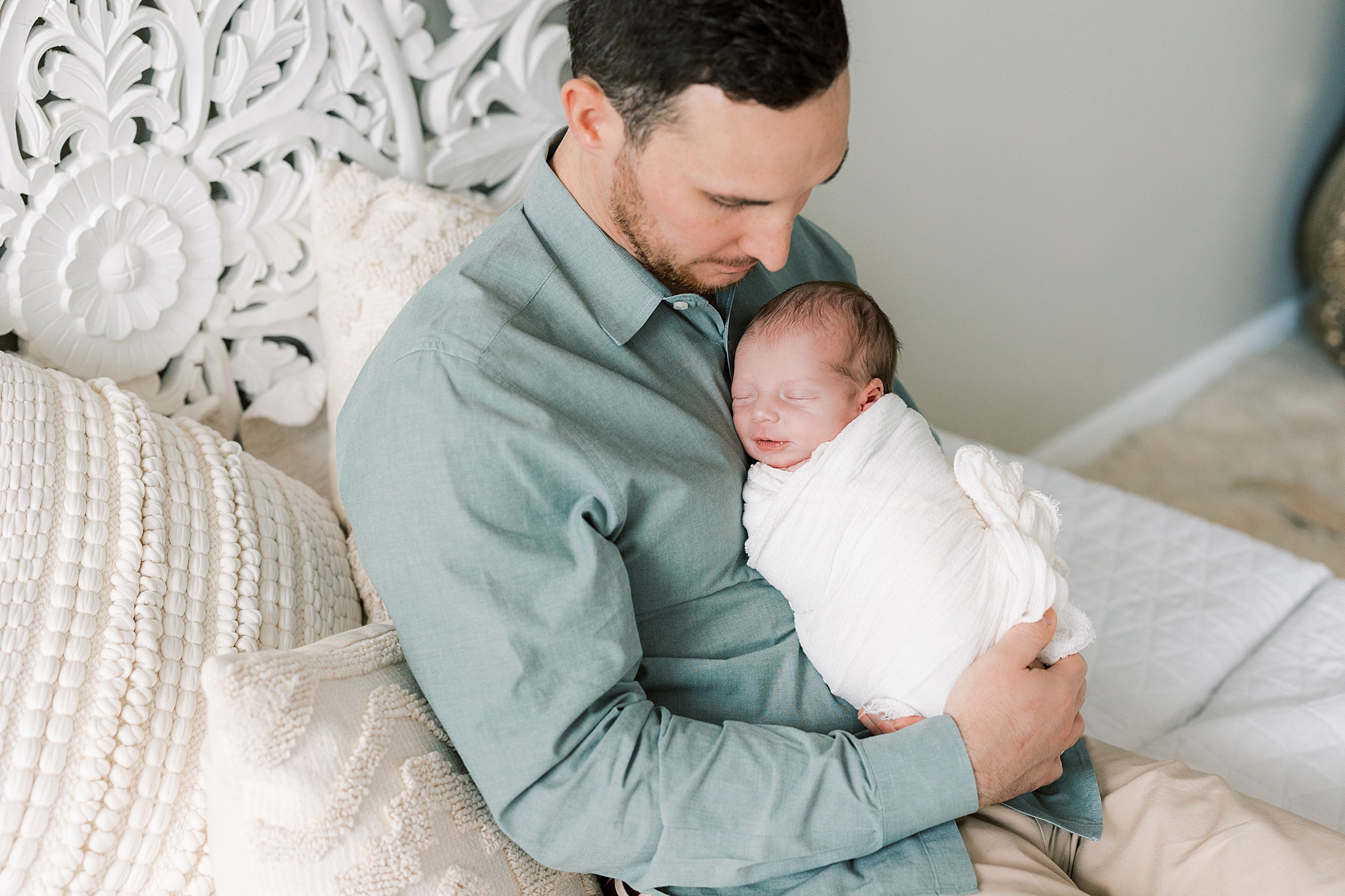 dad in green shirt holds baby girl on chest during studio newborn session in Philadelphia PA