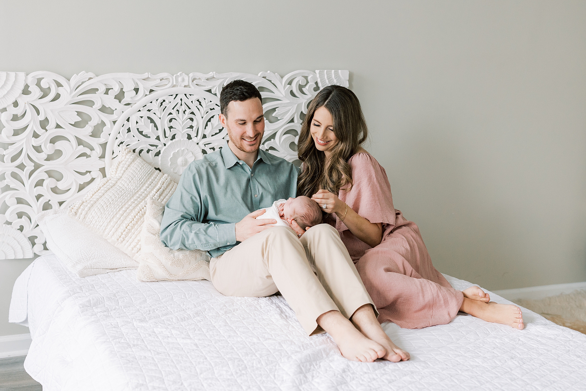 bride and groom sit on bed during studio newborn session in Philadelphia PA