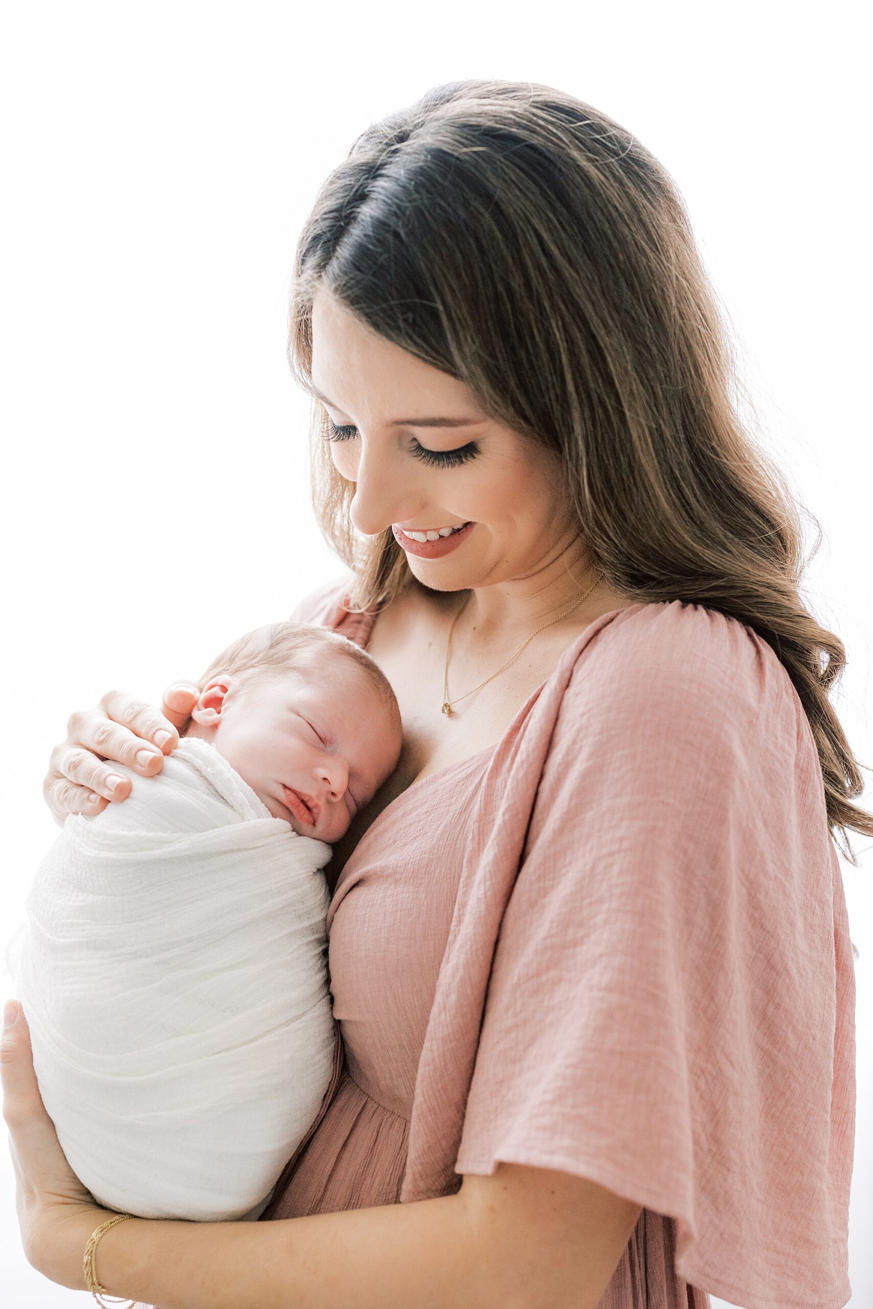 woman holds daughter on chest during studio newborn photos 