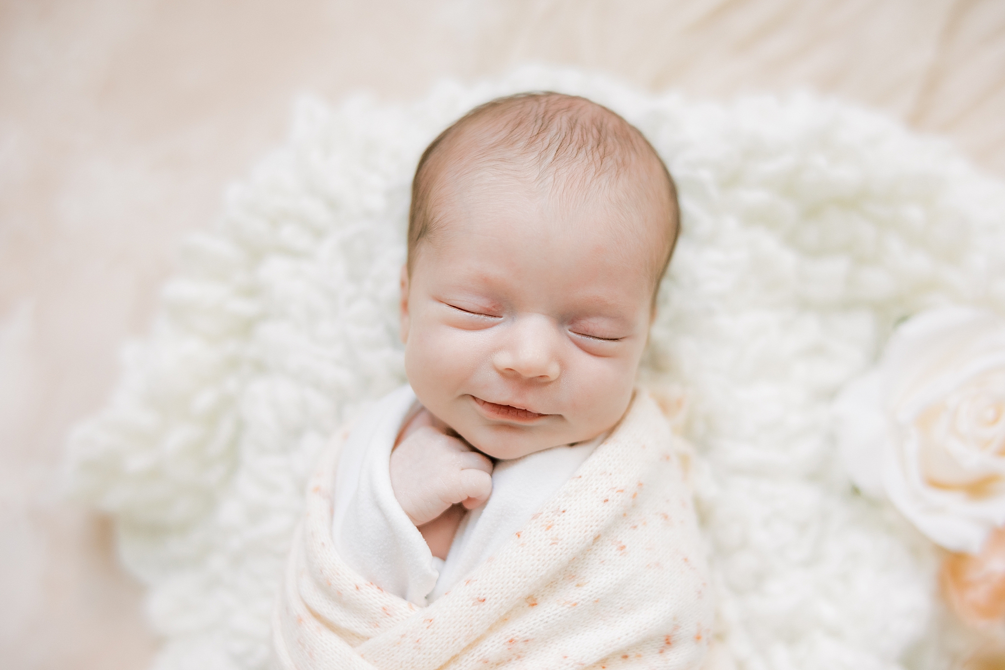 baby lays on white blanket during studio newborn session 