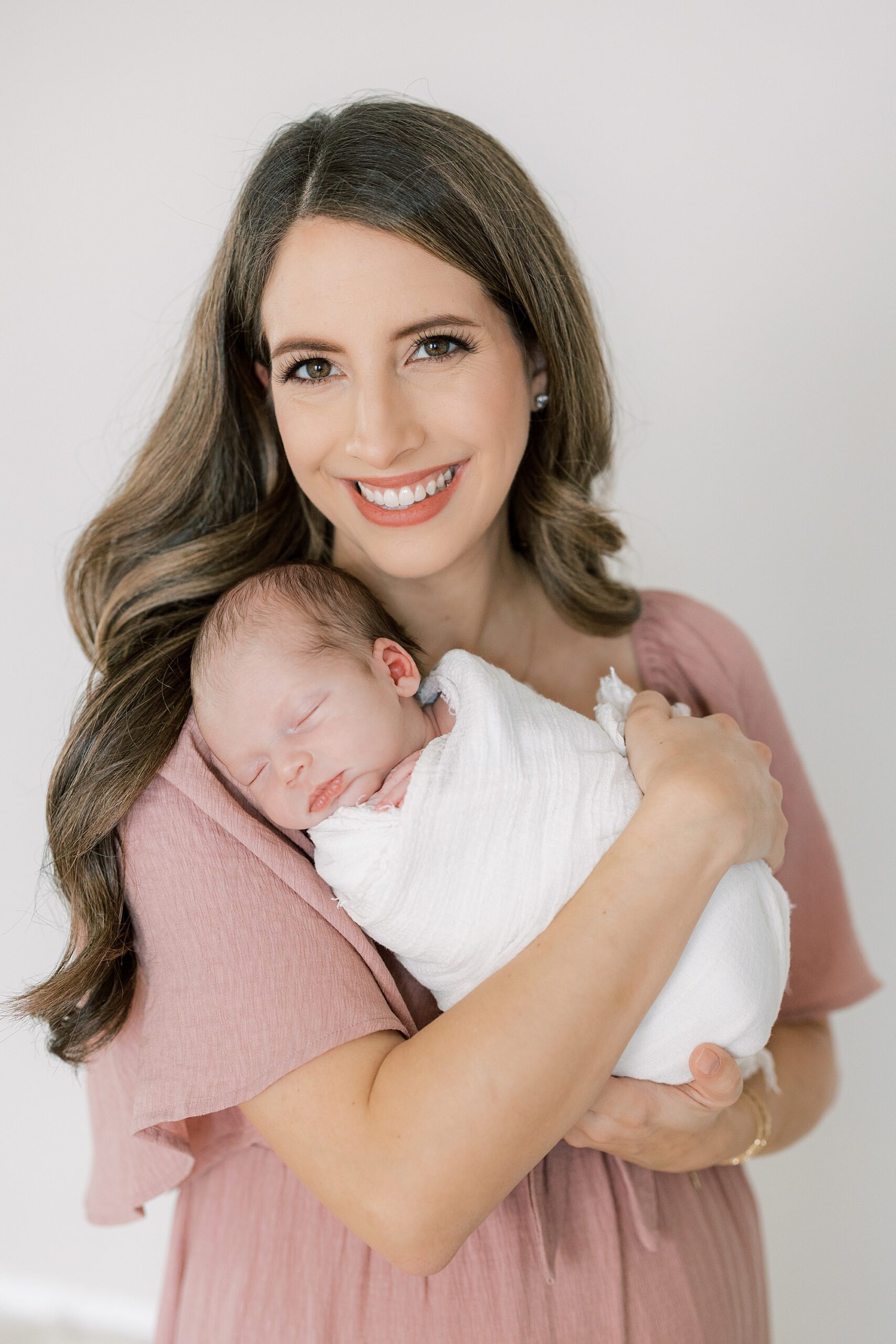 mother in pink gown holds baby girl during studio newborn session in Philadelphia PA