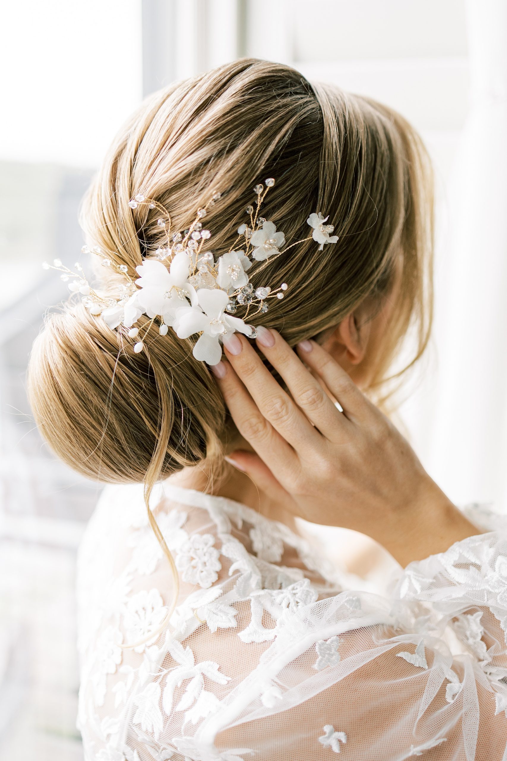 bride adjusts white floral headpiece before wedding