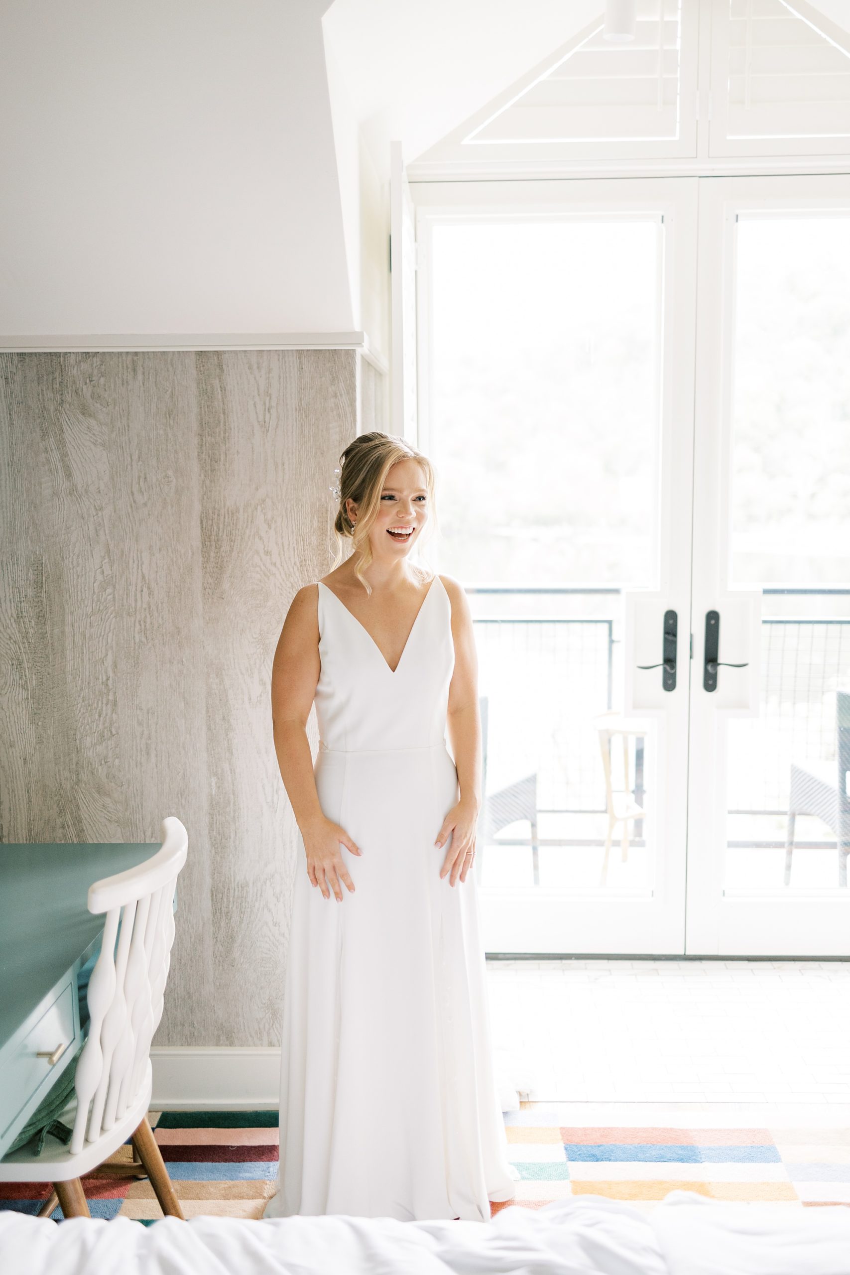 bride stands in wedding gown by windows 