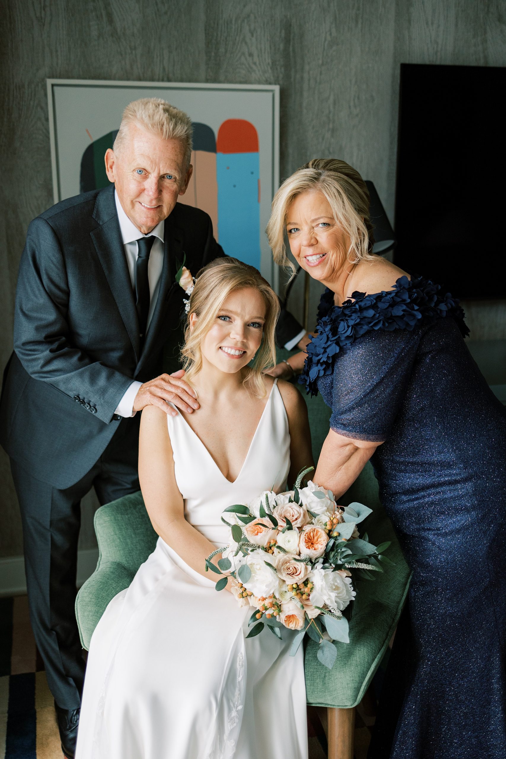 bride poses with parents in bridal suite 