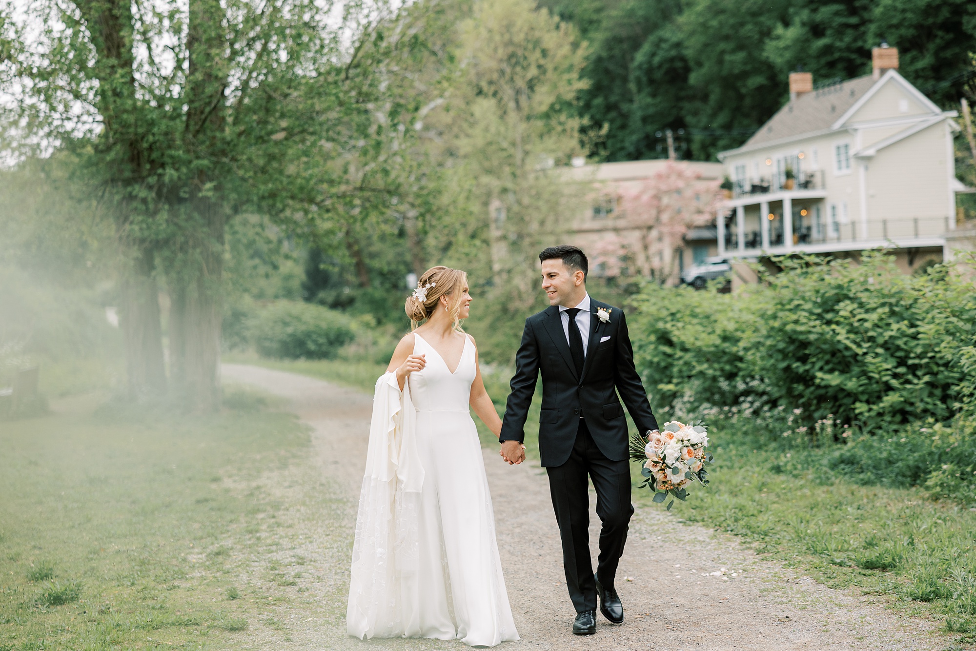 newlyweds hold hands walking in front of The River House at Odette's
