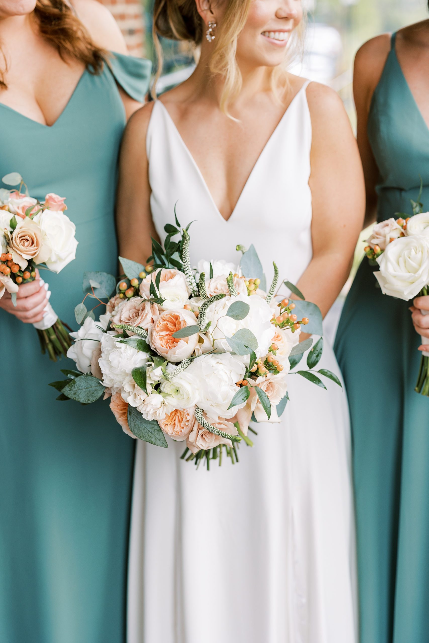bride and bridesmaids hold bouquets of peach and ivory peonies 