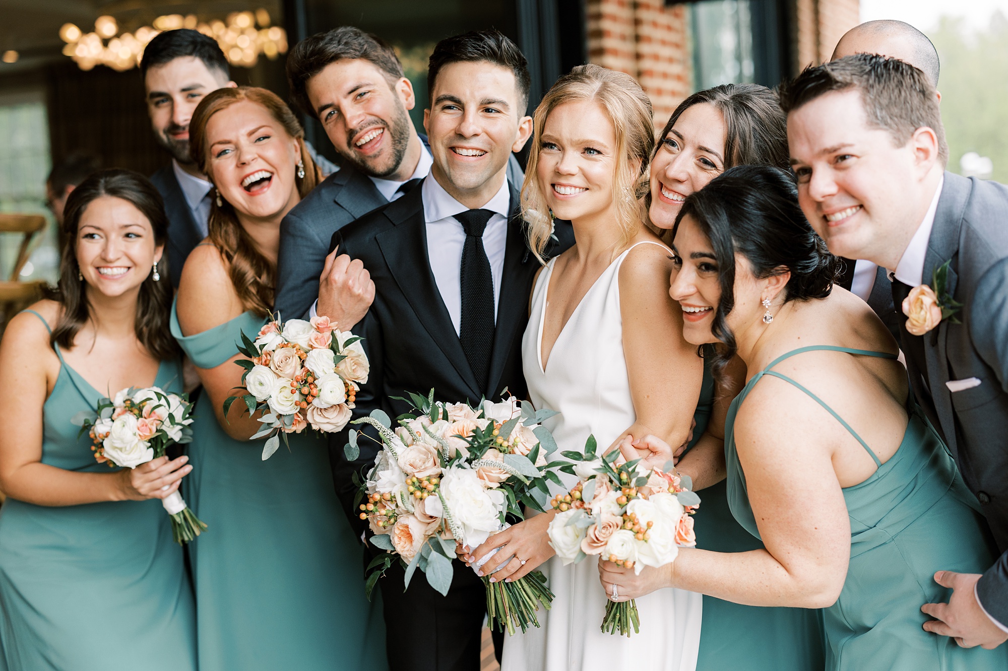 bridal party hugs around bride and groom on wedding day 