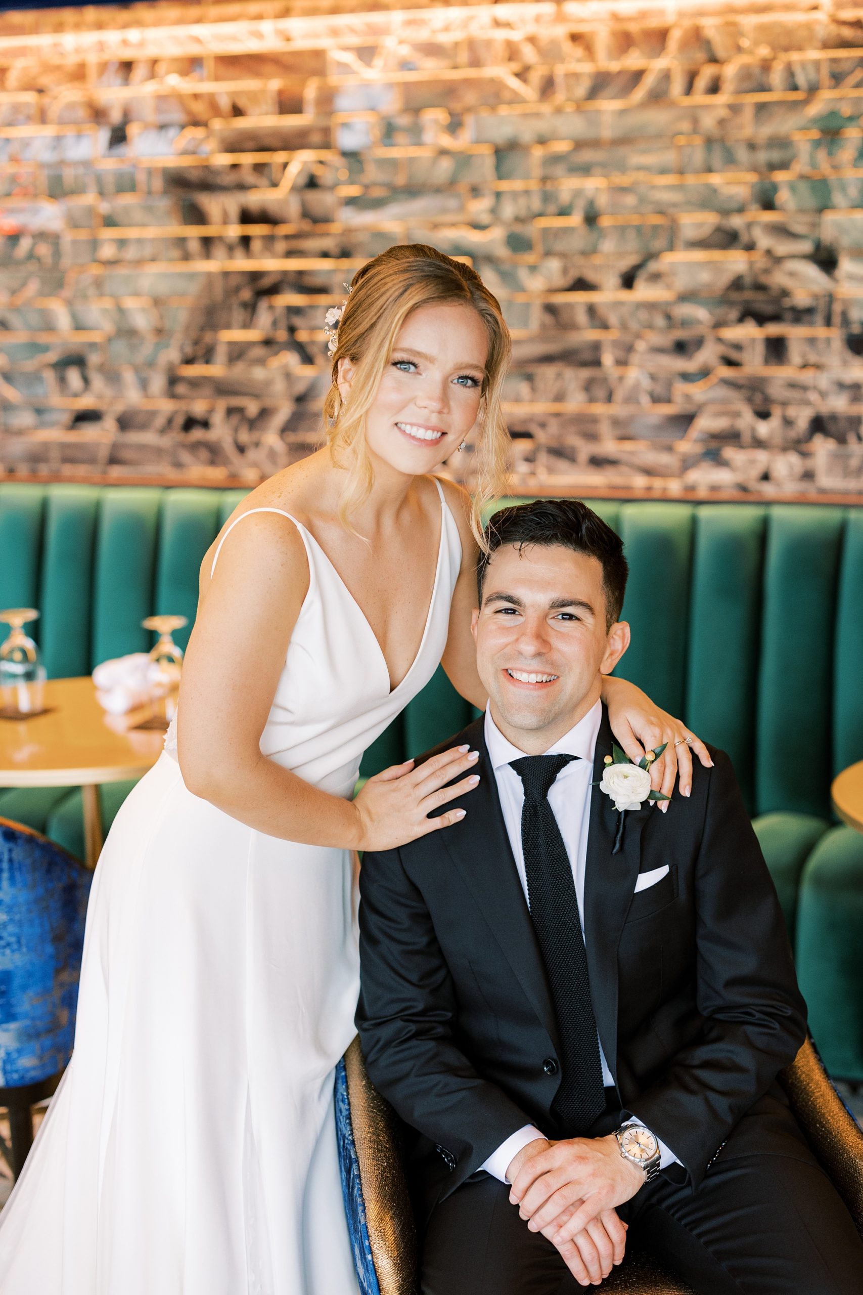 bride and groom sit inside The River House at Odette's on teal couch 
