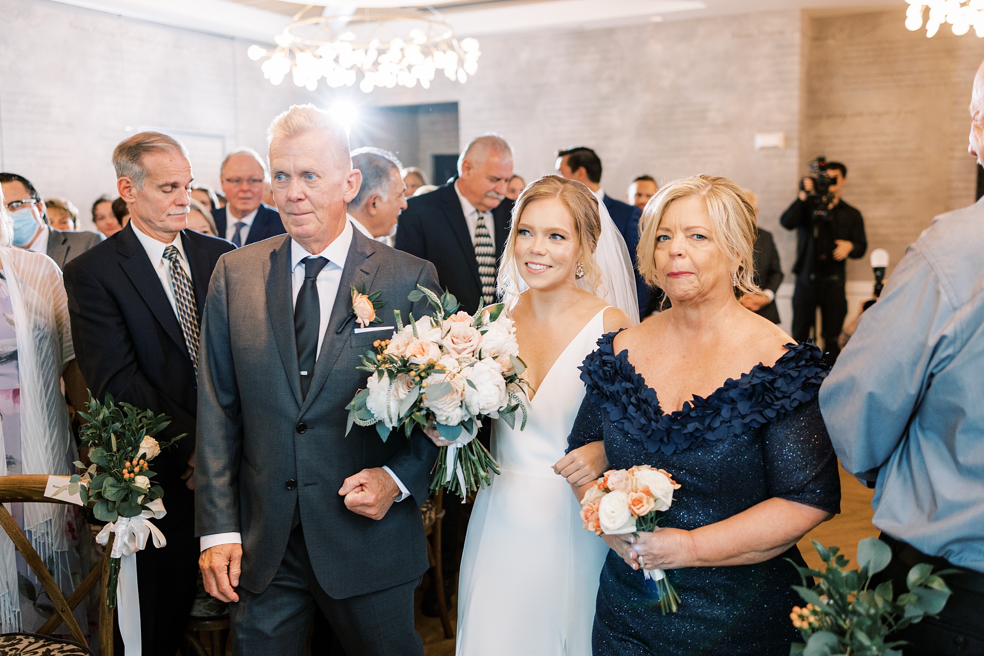 bride walks into wedding ceremony with parents 