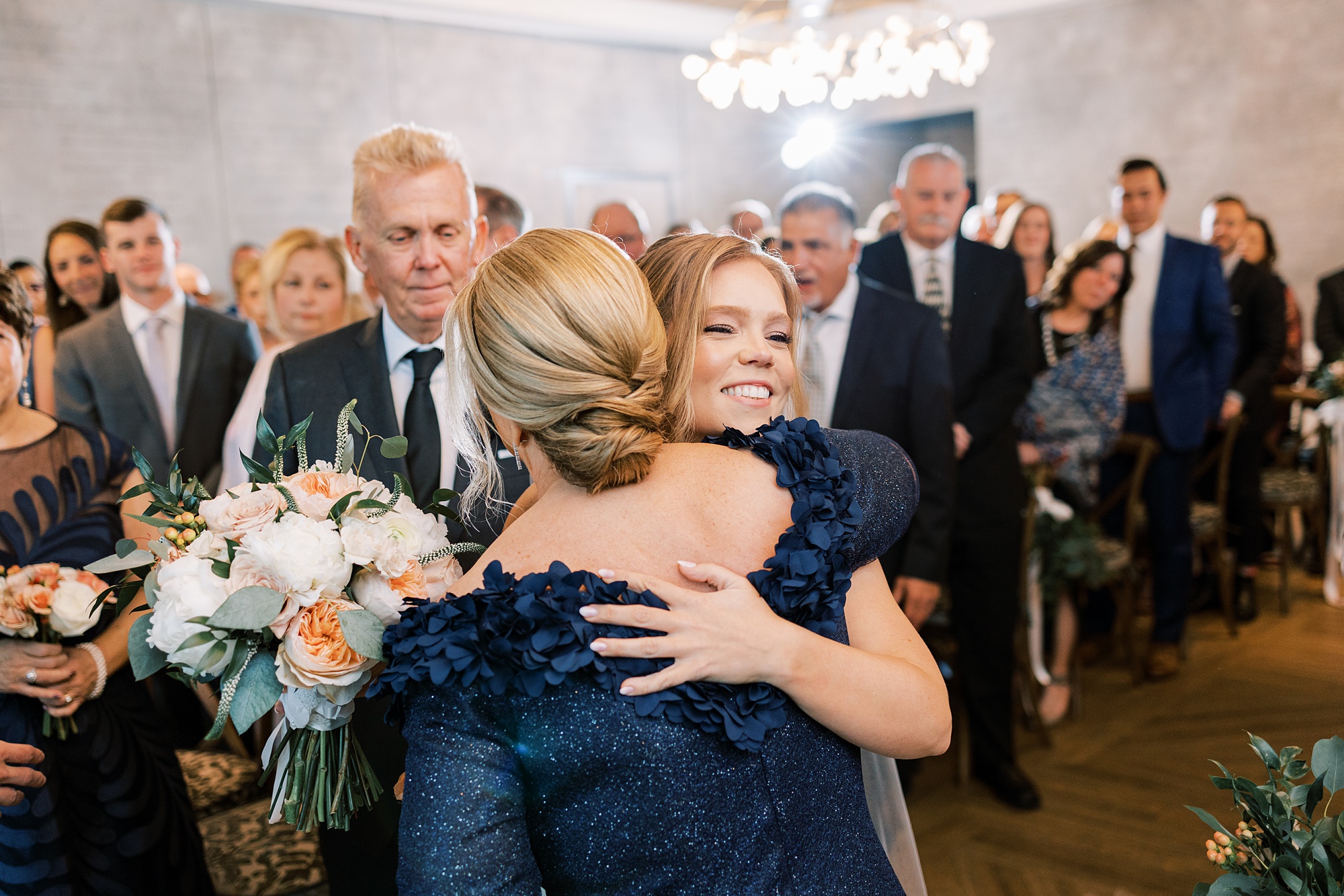 bride hugs mother in navy gown during wedding ceremony in New Hope PA
