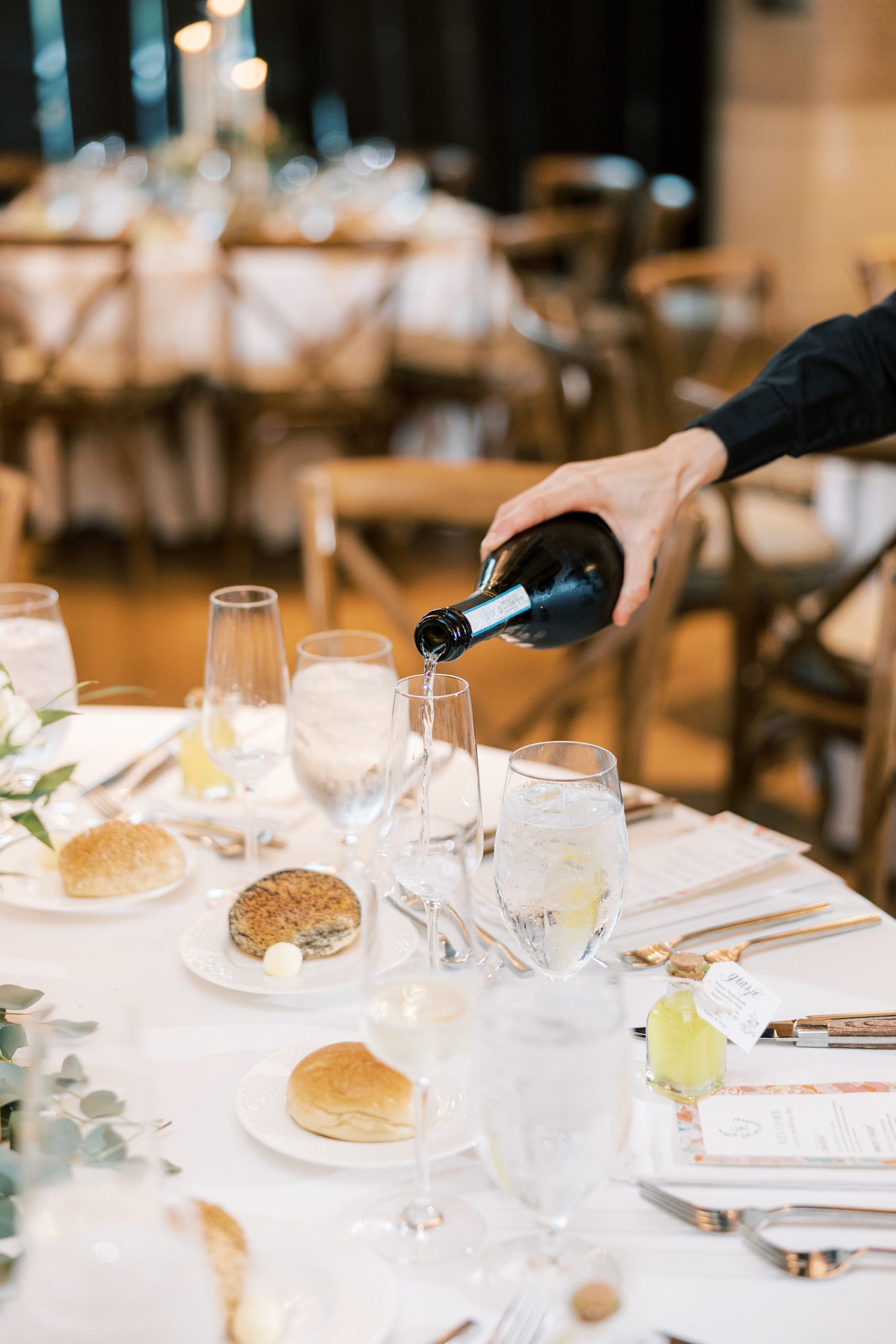 waiter pours wine for Italian inspired wedding reception at The River House at Odette's