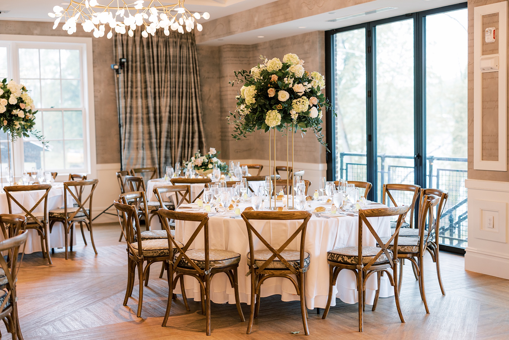 wedding reception with wooden chairs and tall flower centerpiece 