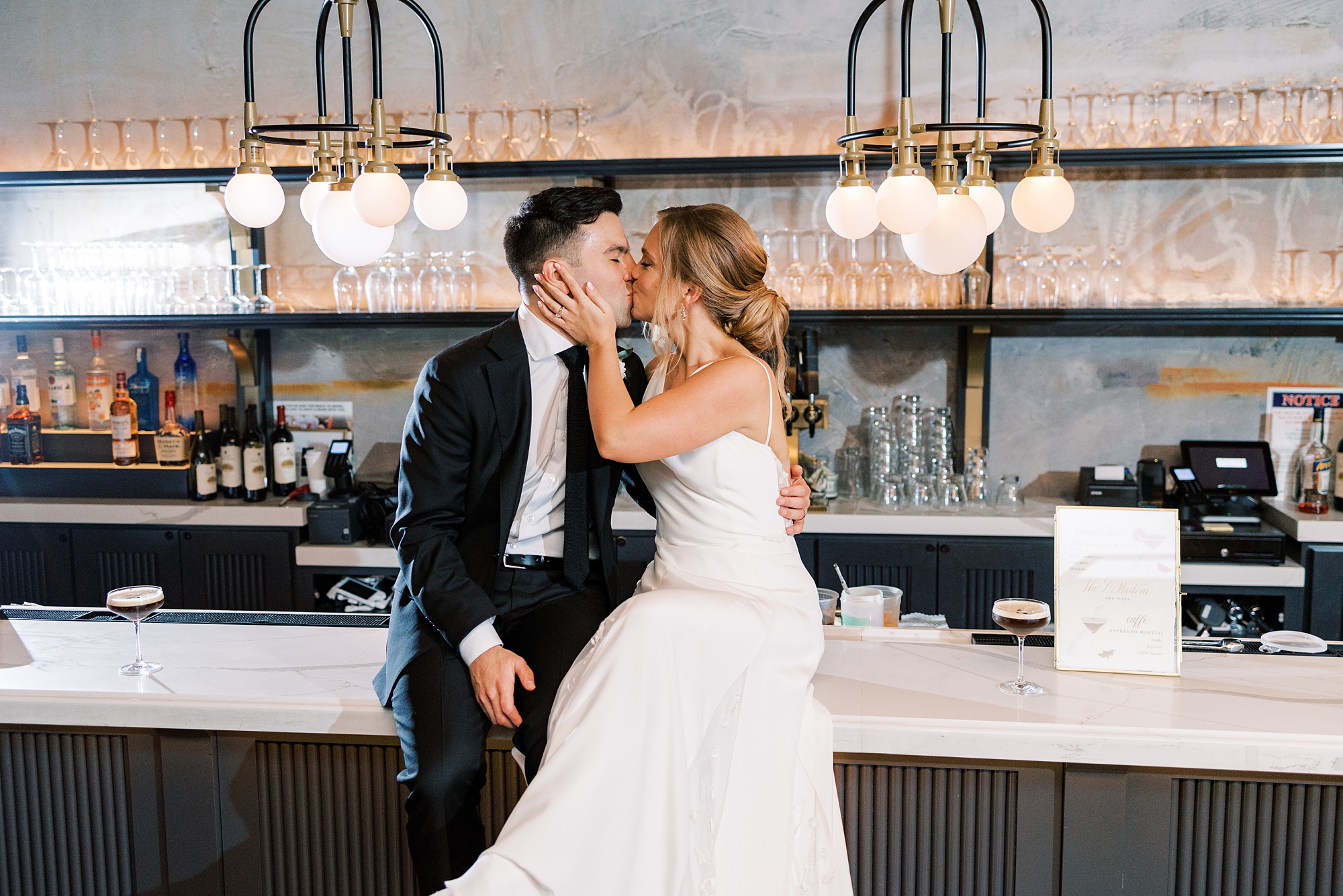 bride and groom kiss on bar at the River House at Odette's