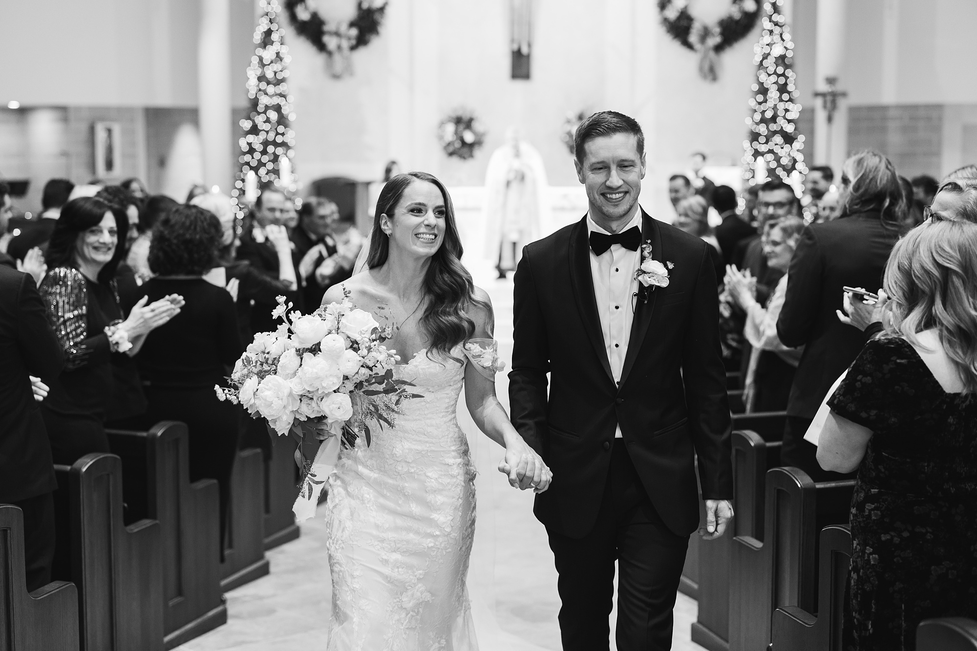 newlyweds laugh and smile walking up aisle of church 