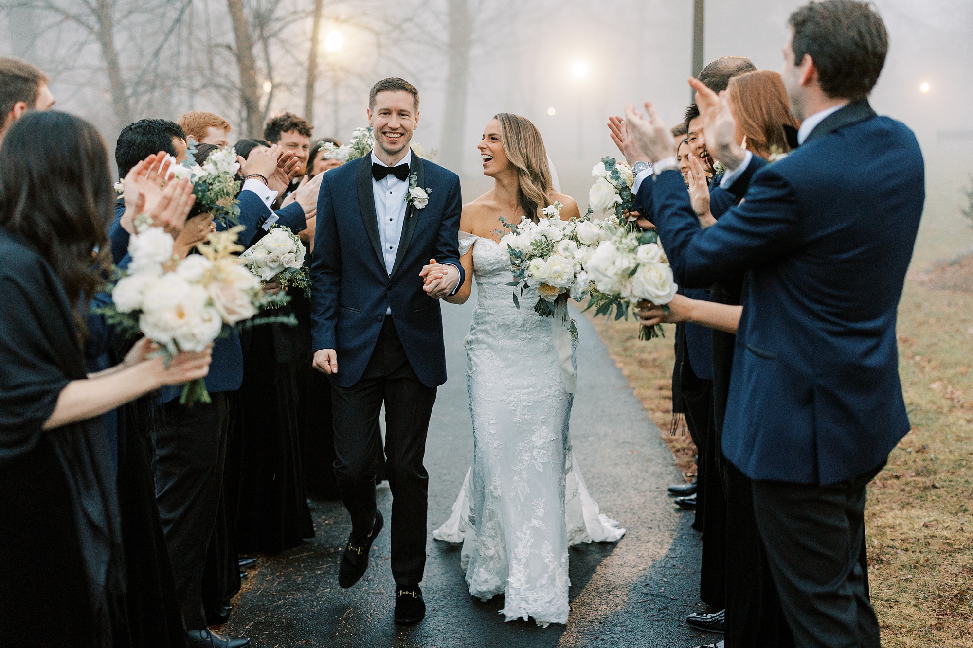 bride and groom hold hands walking between wedding party cheering in New Jersey park