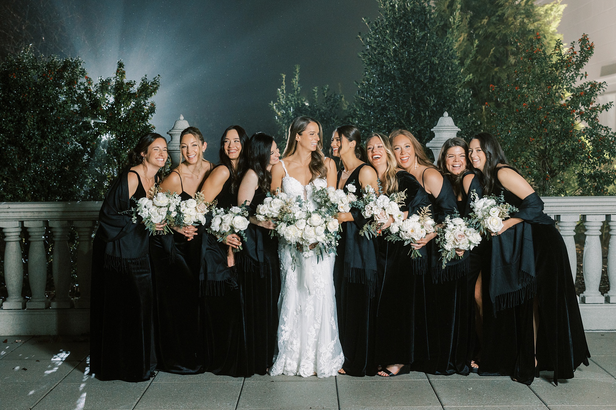 bride laughs with bridesmaids cuddled together in New Jersey park
