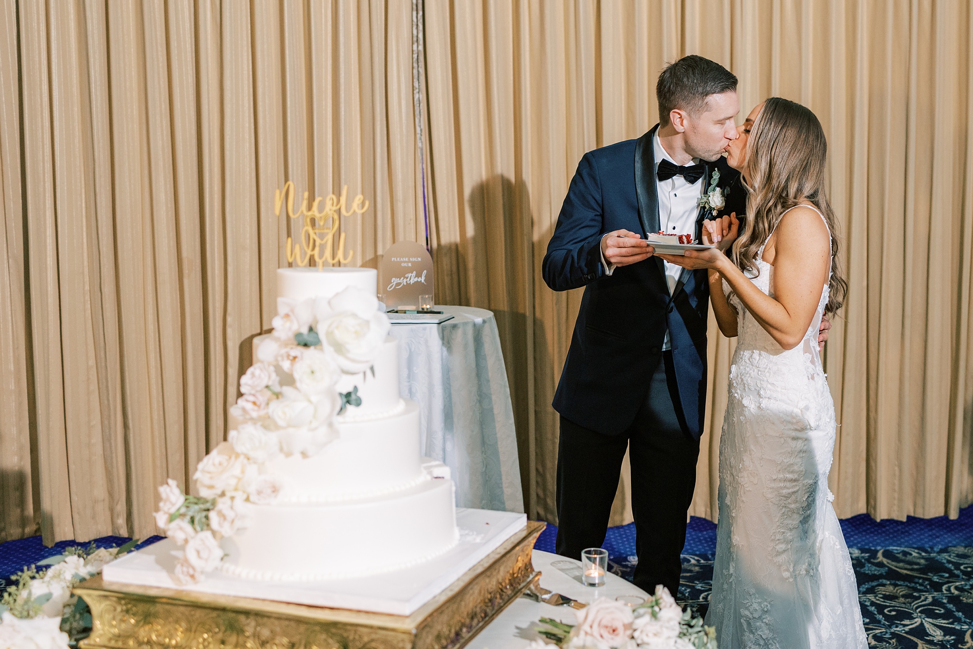 bride and groom kiss by wedding cake at New Jersey wedding reception 