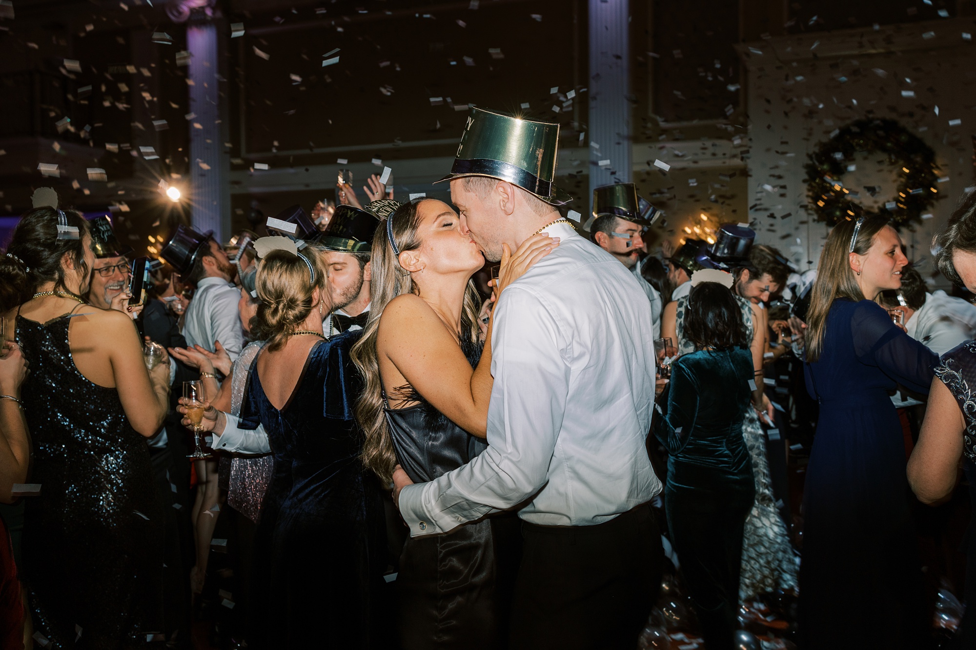bride and groom kiss during ball drop and confetti on New Year's Eve