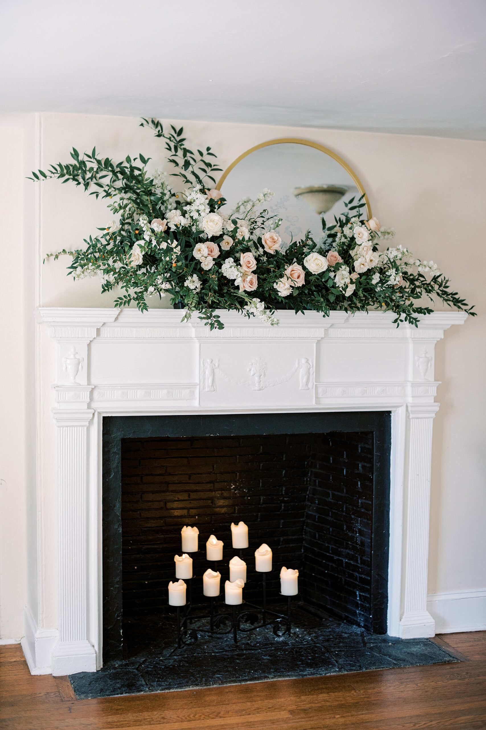 fireplace filled with candles with greenery and rose arrangement on top at Parque Ridley Creek