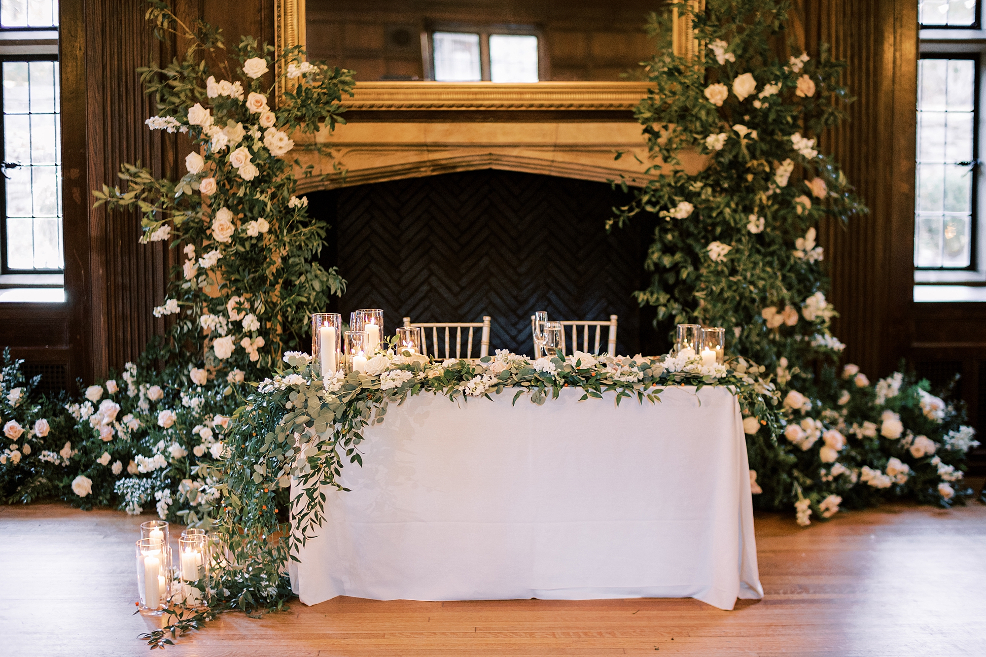 sweetheart table with floral arrangements on either side of fireplace 