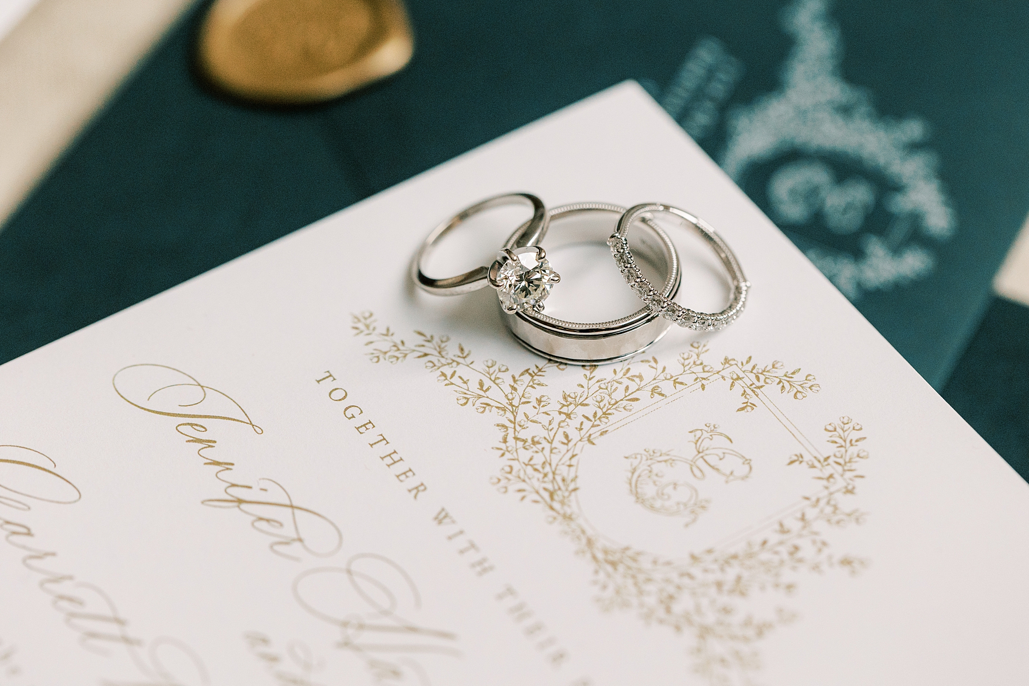 silver wedding rings rest on invitation with custom crest 