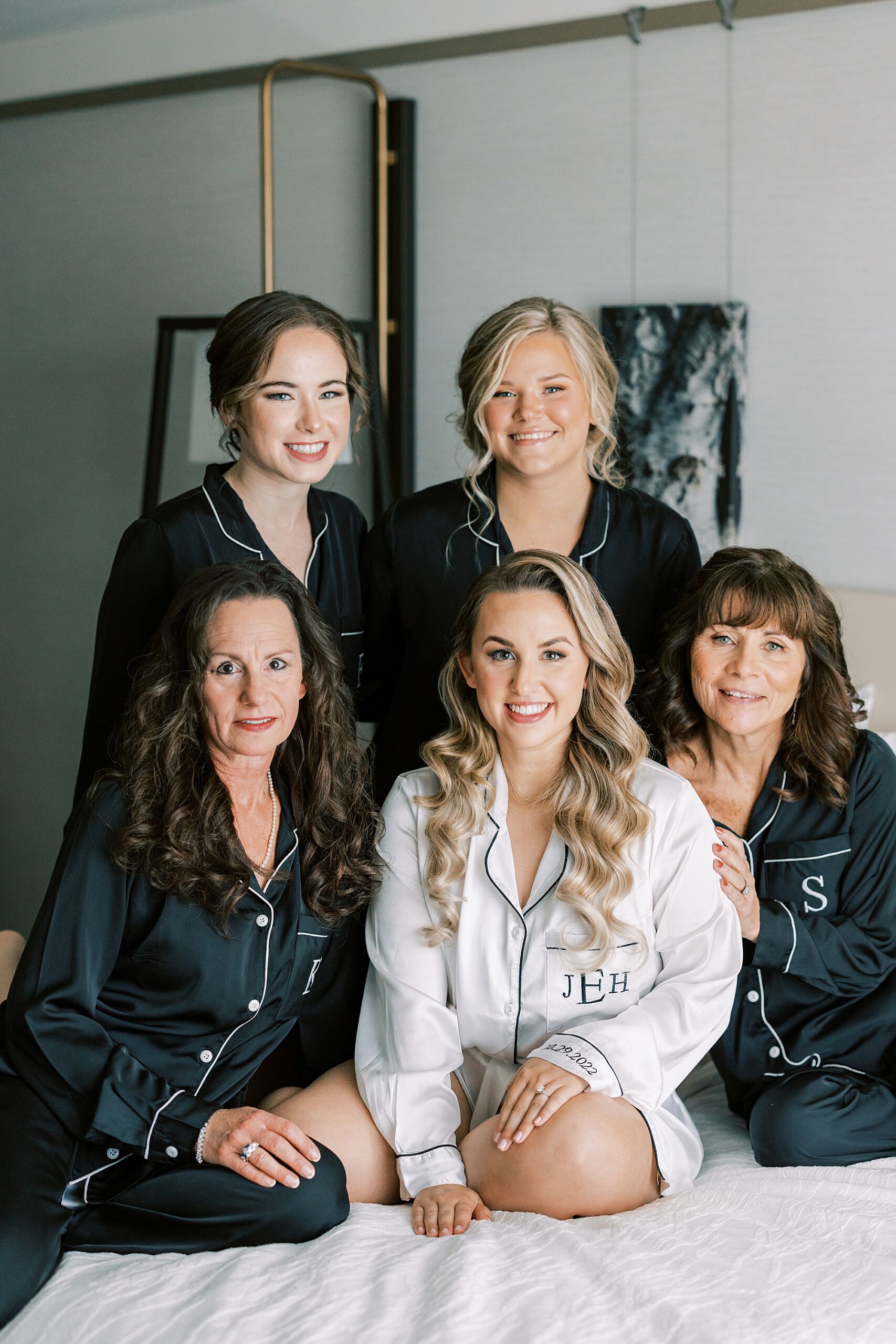 bride sits on bed with bridesmaids in custom pajamas 