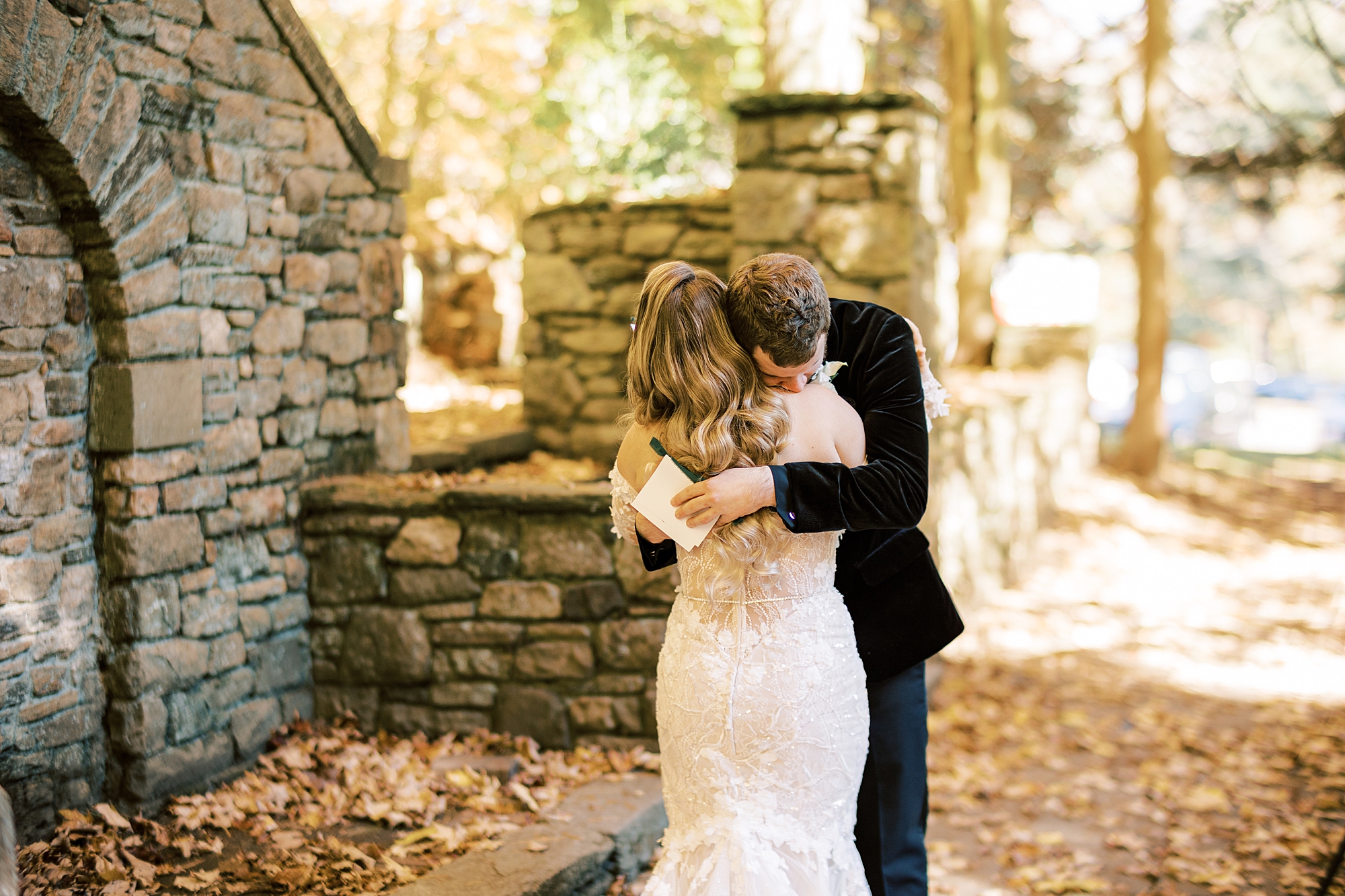 groom hugs bride tightly by stone wall at Parque Ridley Creek