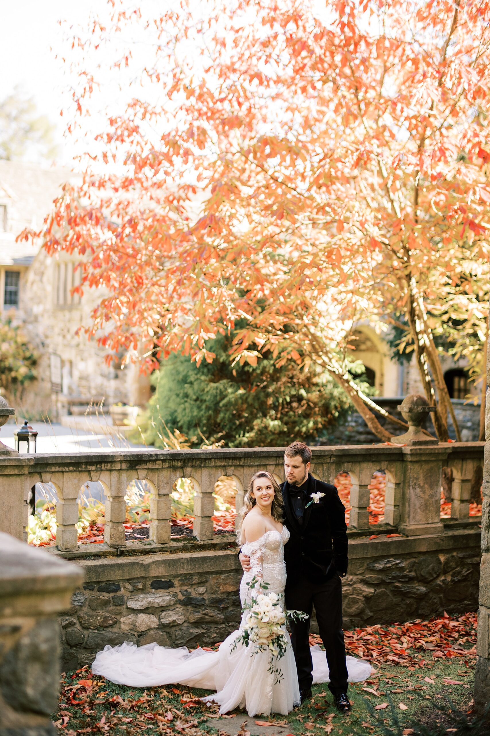 bride and groom pose by stone bridge with orange leaves at Parque Ridley Creek