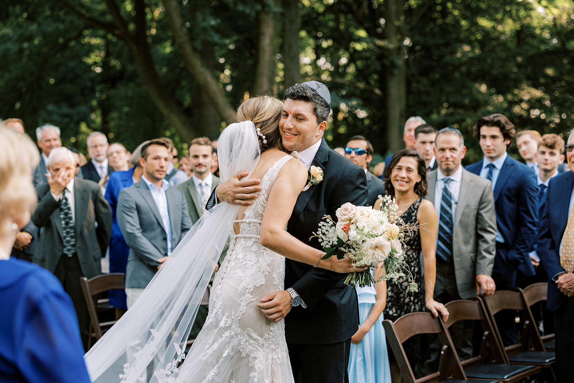 bride and groom hug during Curtis Arboretum wedding ceremony on lawn