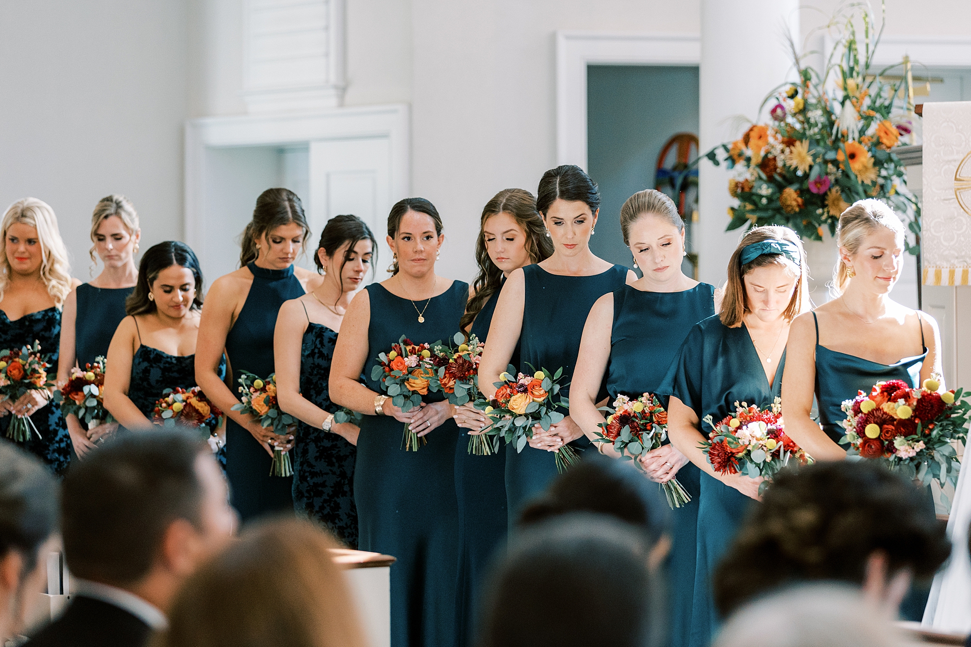 bridesmaids in teal dresses listen to ceremony in church 
